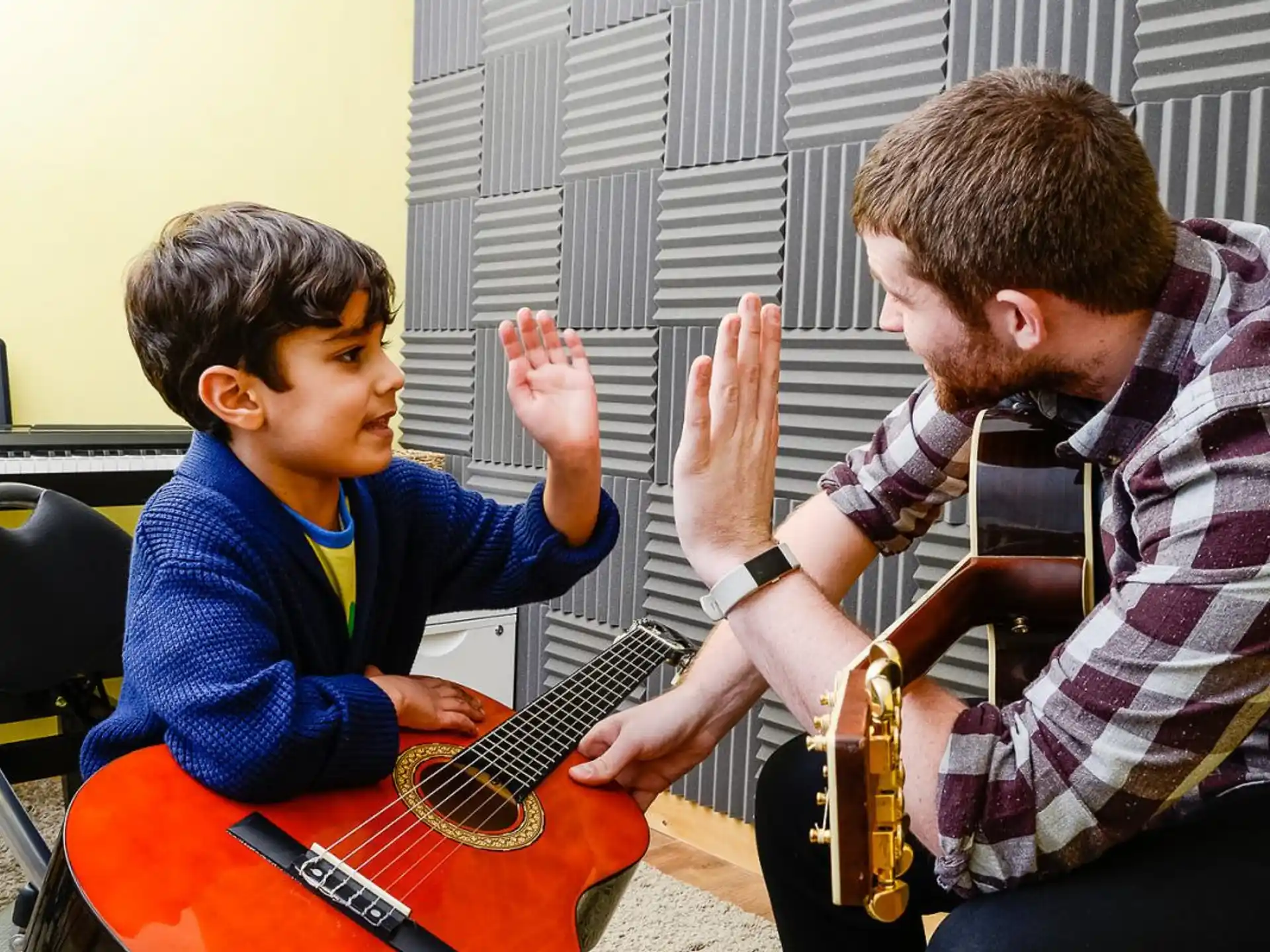 a man playing guitar to a boy