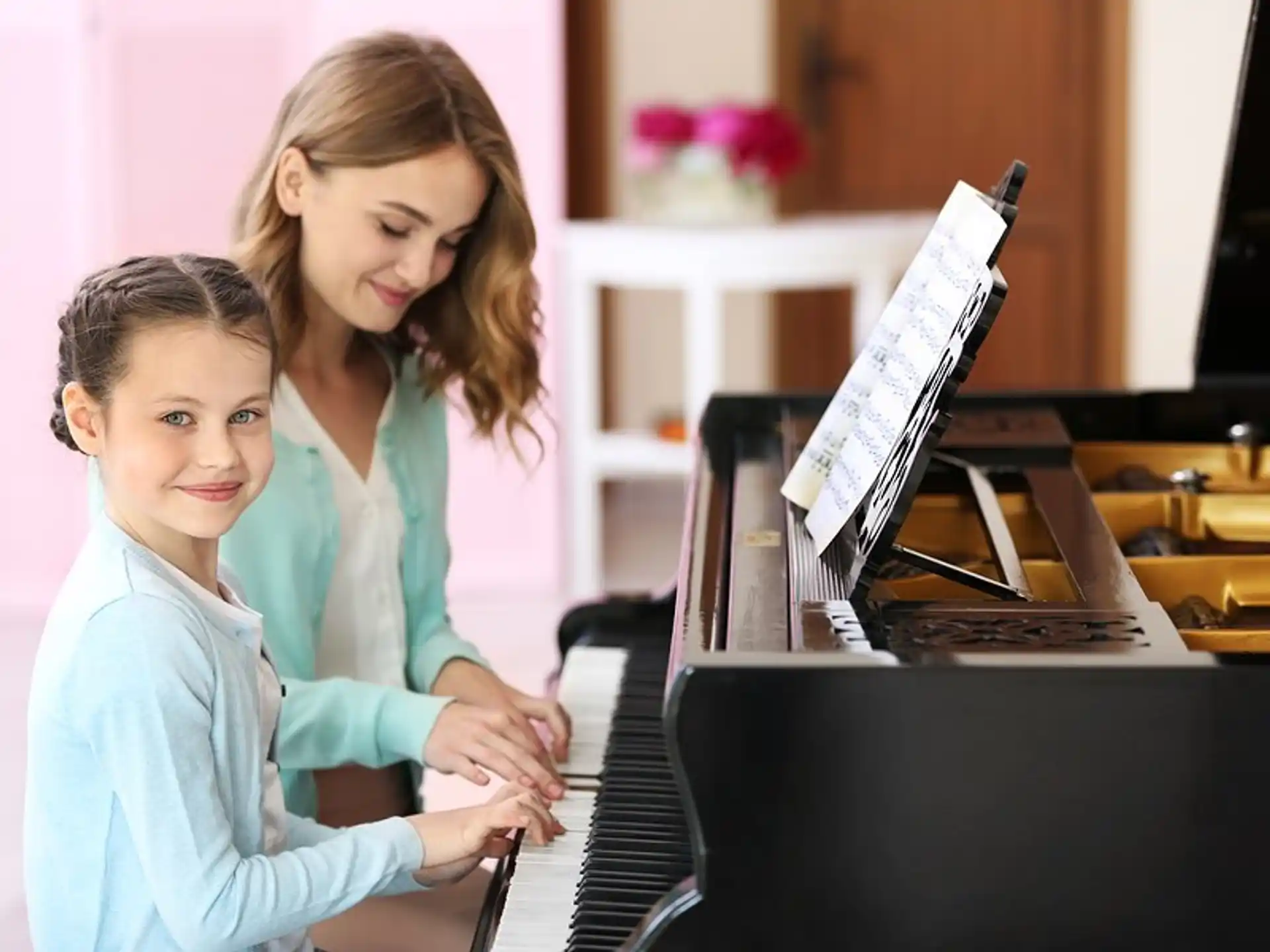 a woman and a girl playing piano