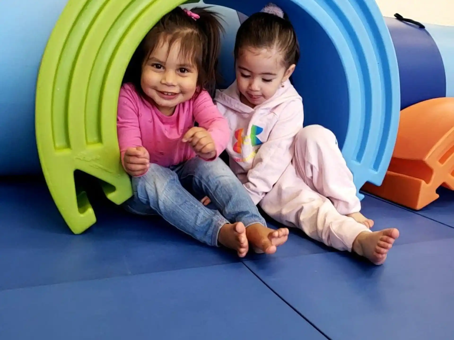 a couple of children sitting on a blue mat