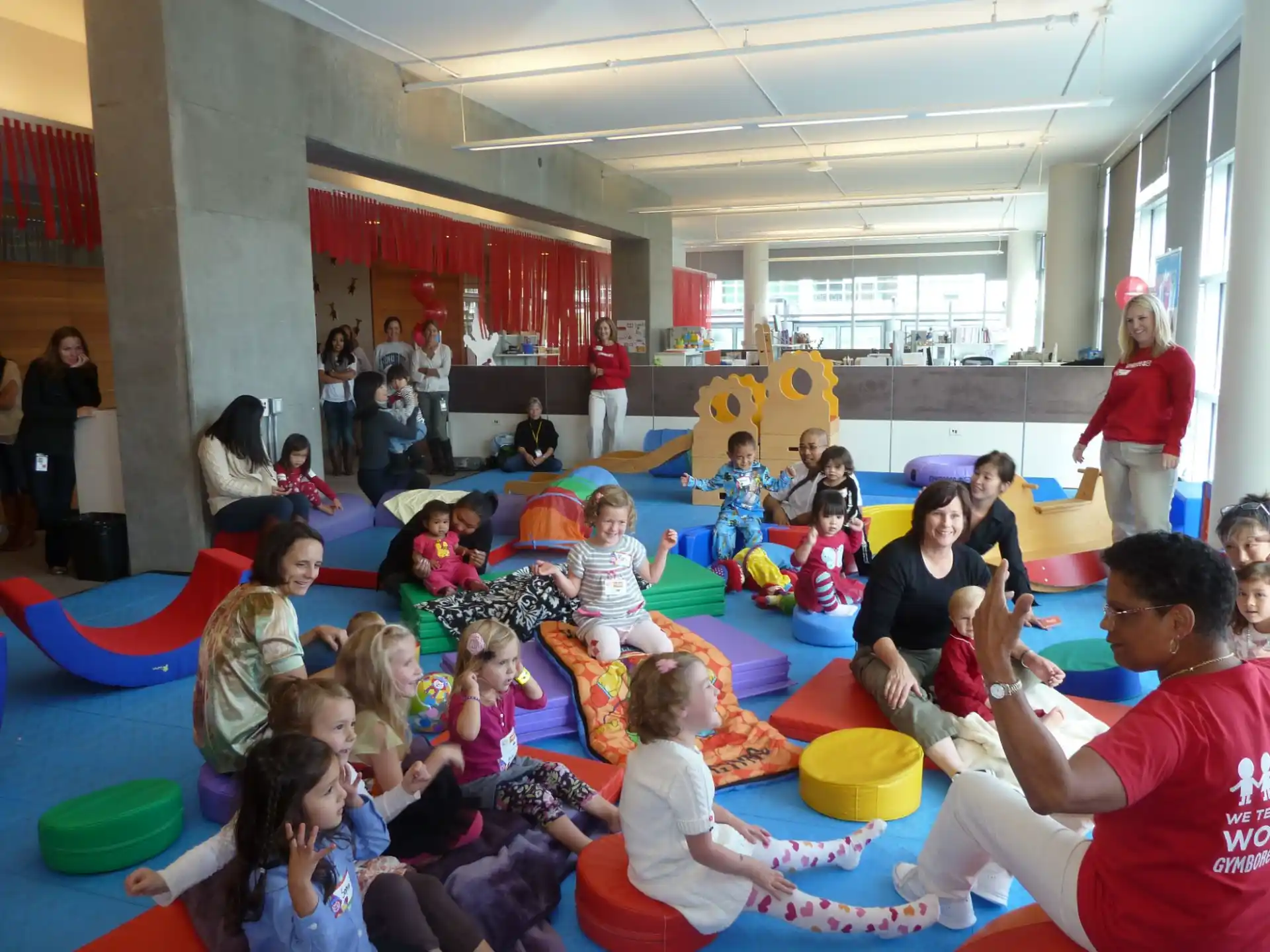 a group of people sitting on red and blue mats in a room