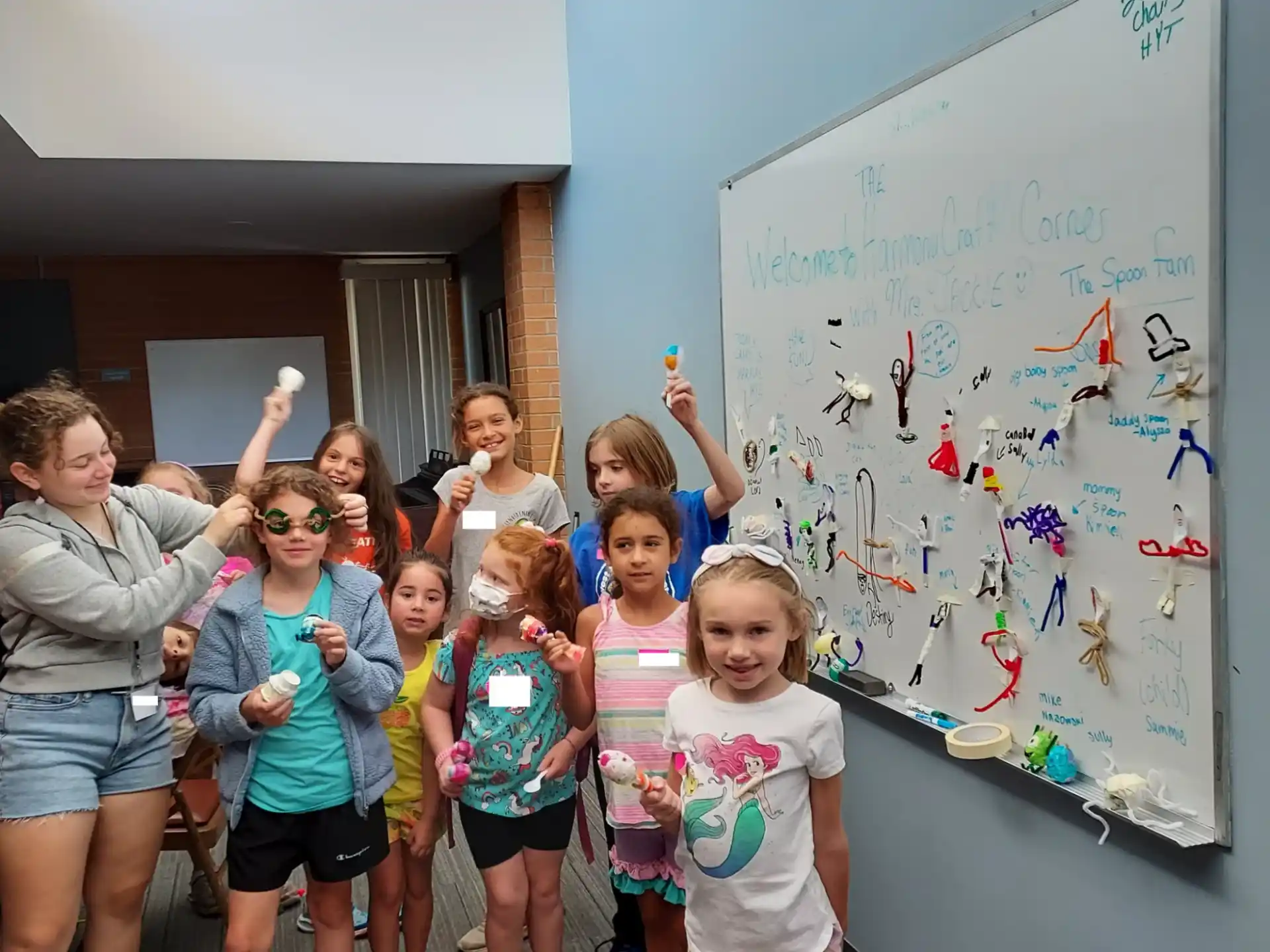 a group of children posing for a photo in front of a white board