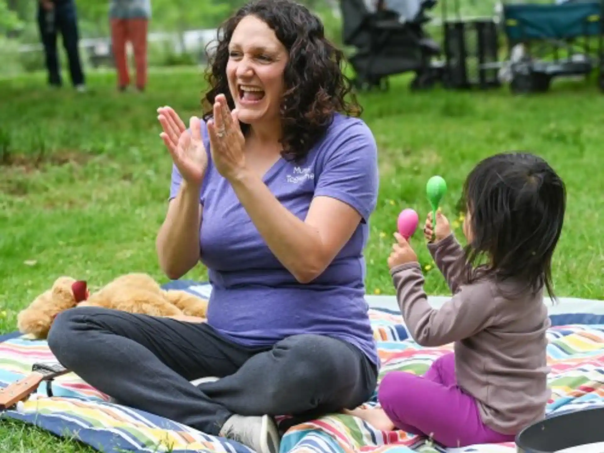 a person and a child sitting on a blanket in a grassy area