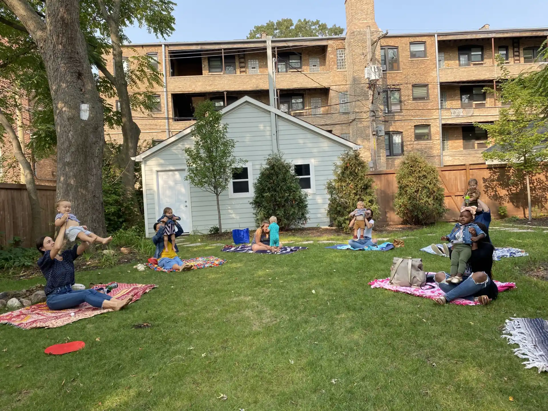 a group of people sitting on the grass in front of a building