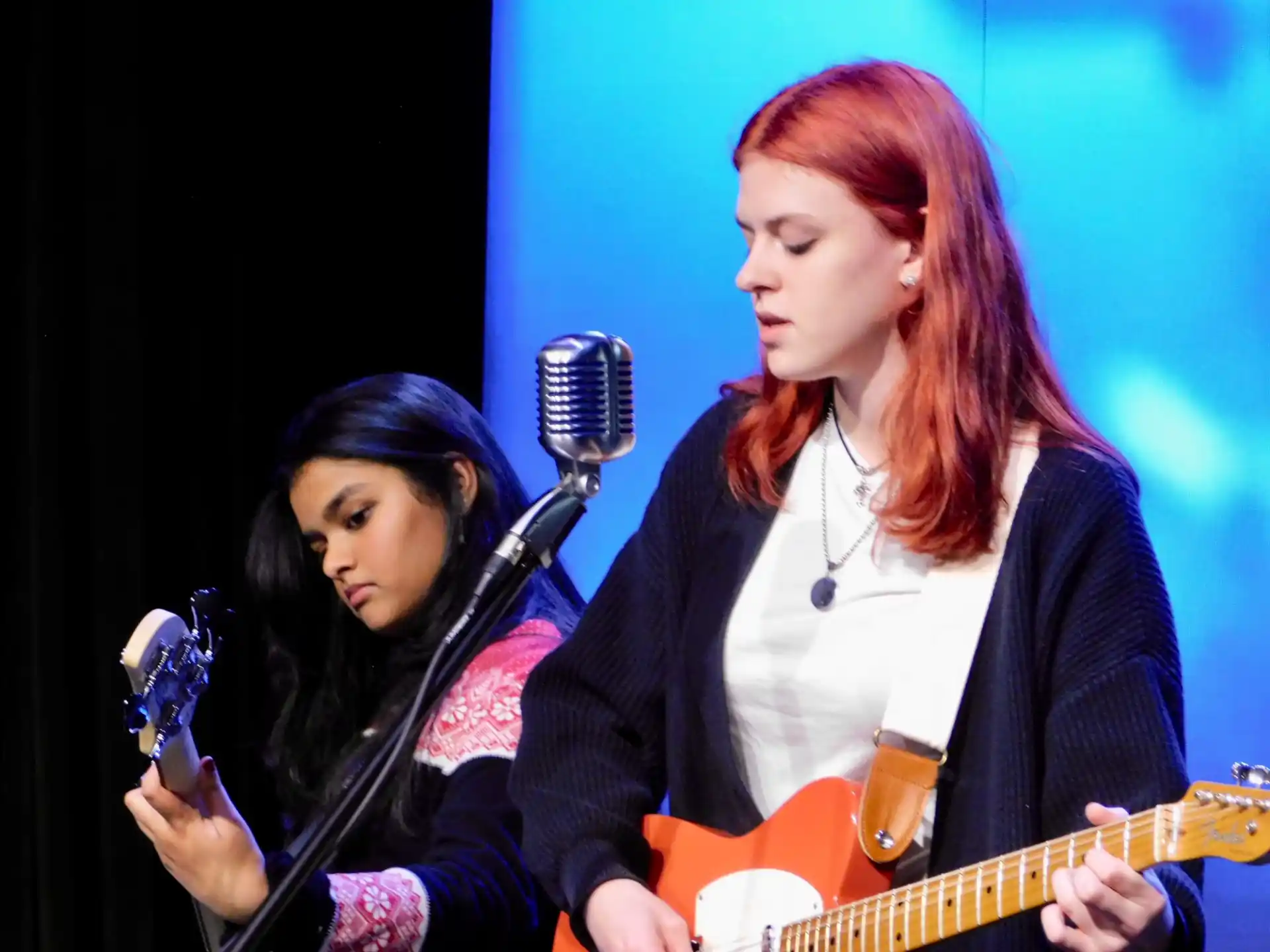 a person singing into a microphone next to a person playing guitar