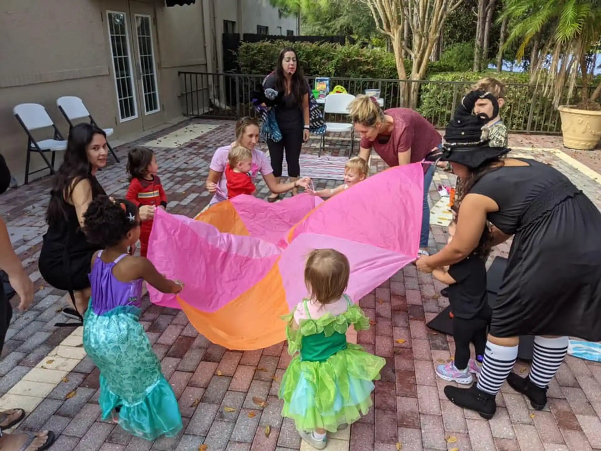 a group of people around a girl holding a pink and white kite