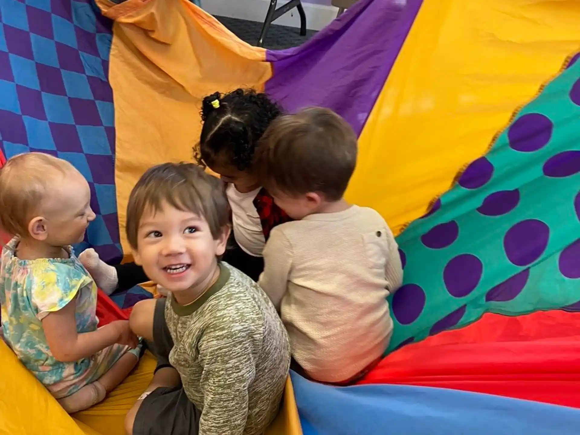 a group of children sitting on a colorful blanket