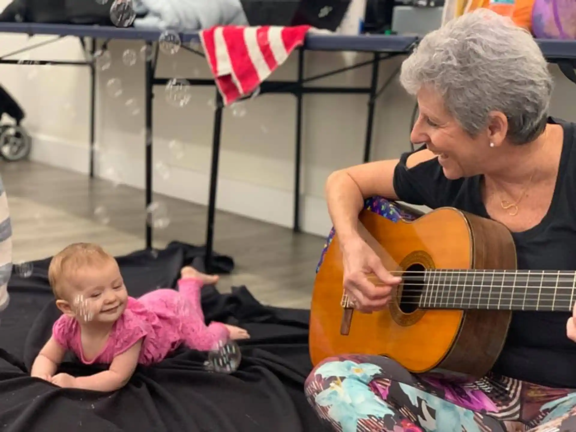 a man playing guitar next to a baby