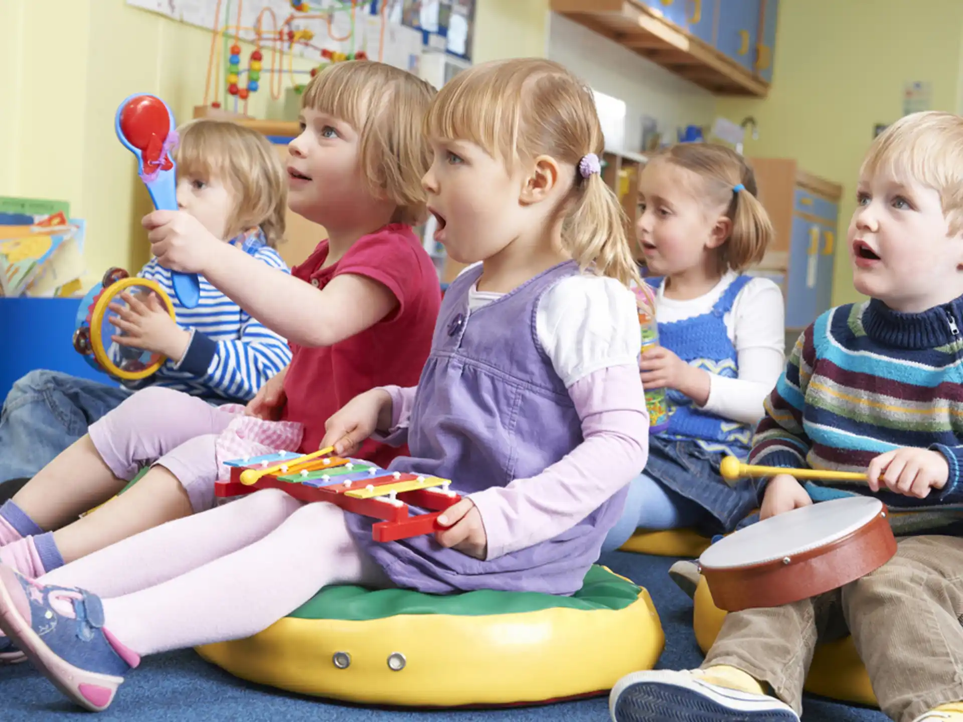 a group of children sitting on a yellow toy in a room