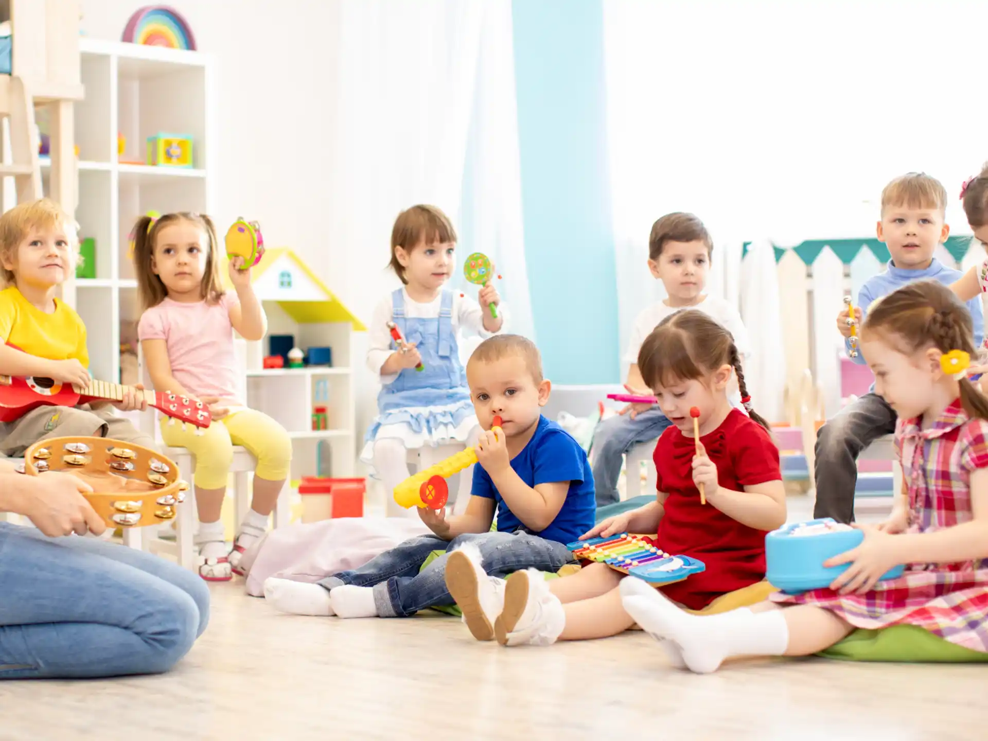 a group of children sitting on the floor playing instruments