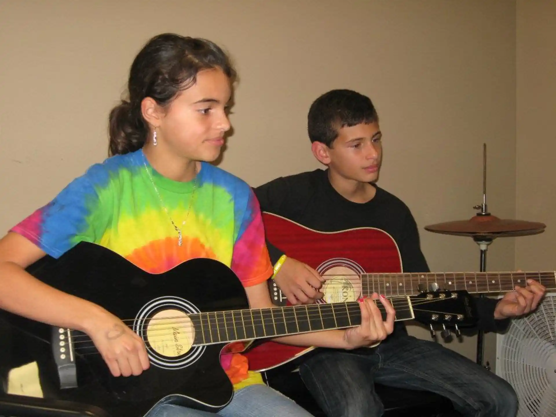 a man playing a guitar next to a boy