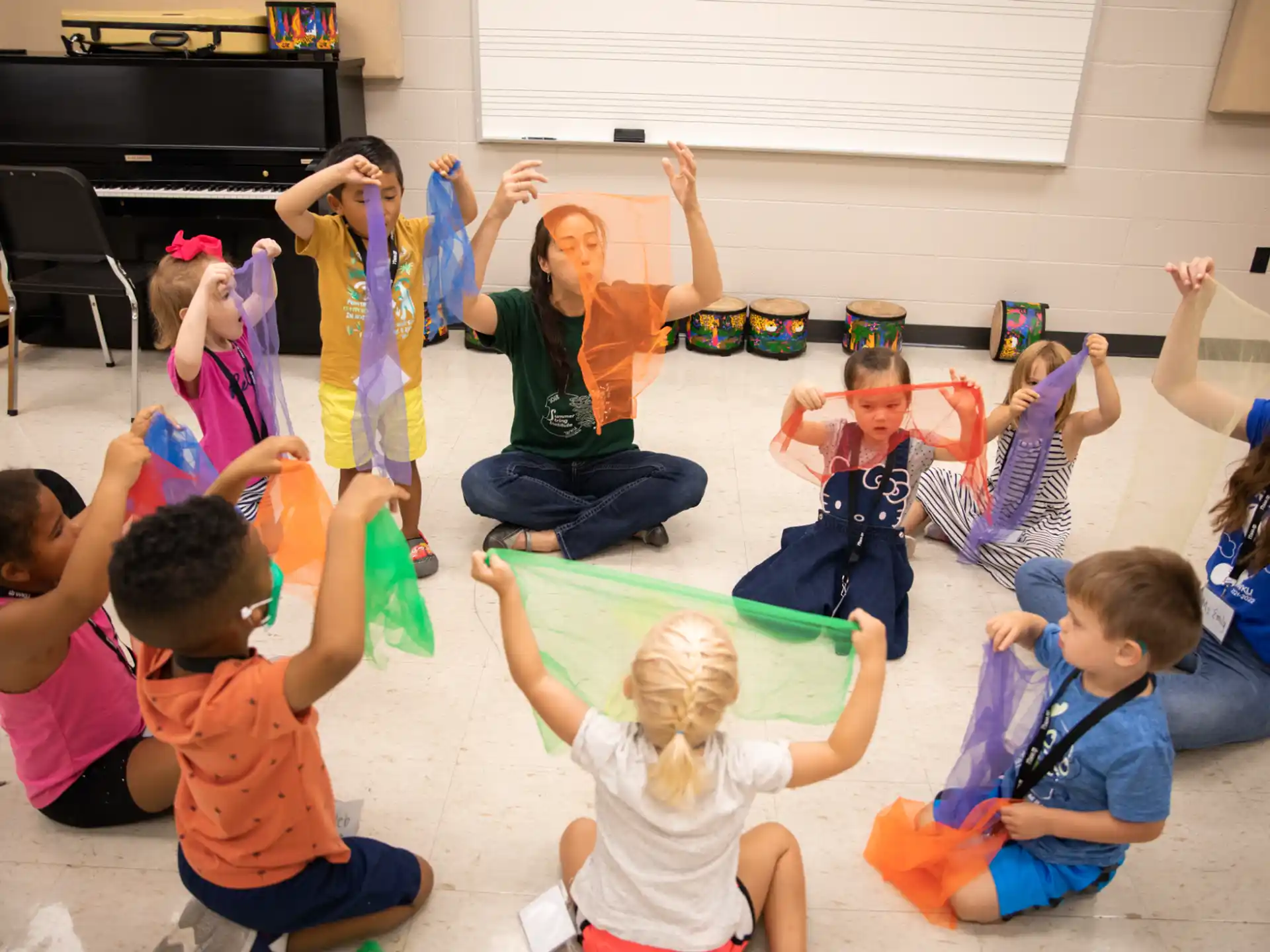 a group of children sitting on the floor with their hands up