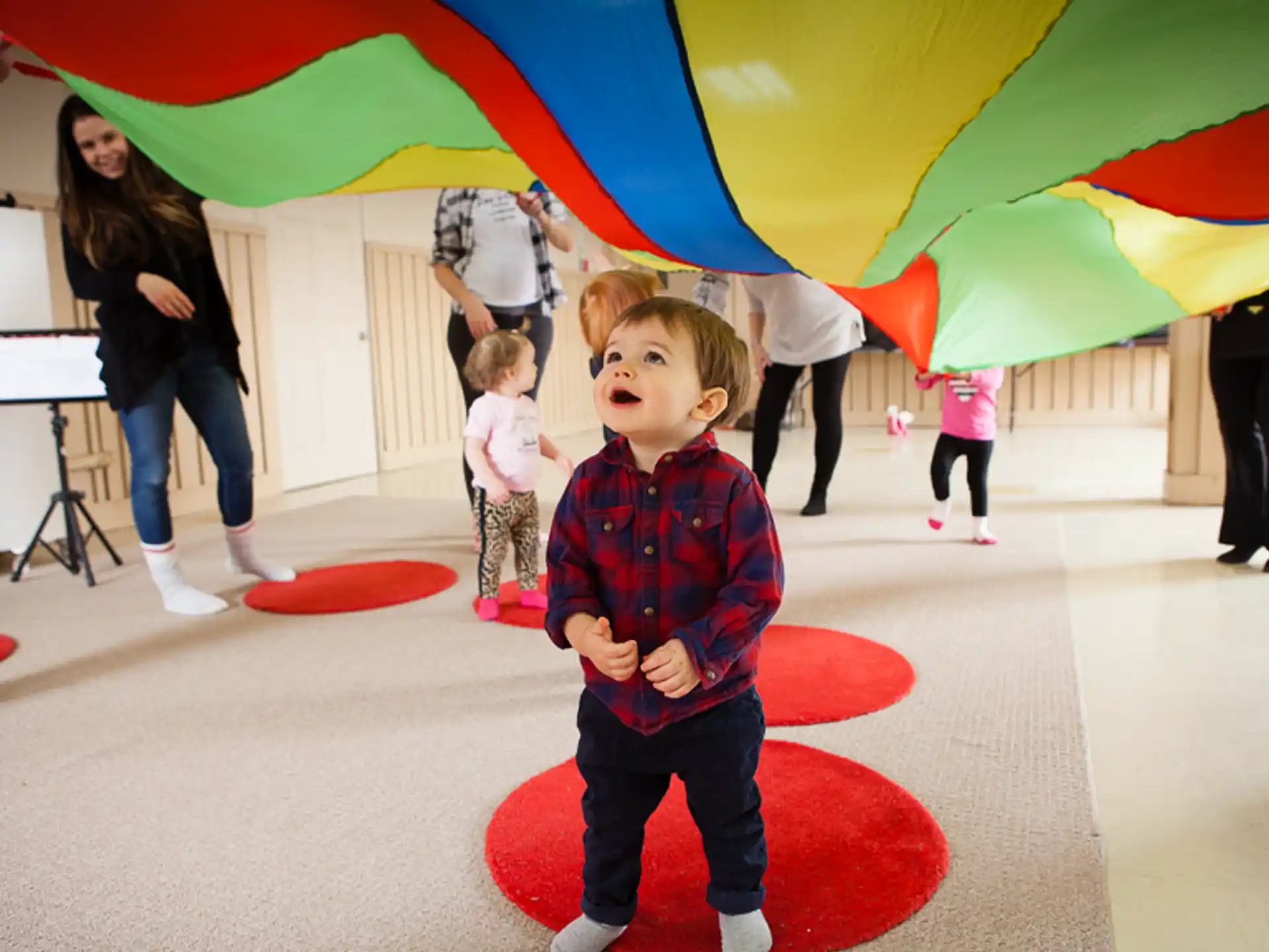 a kid standing in a room with people in the back