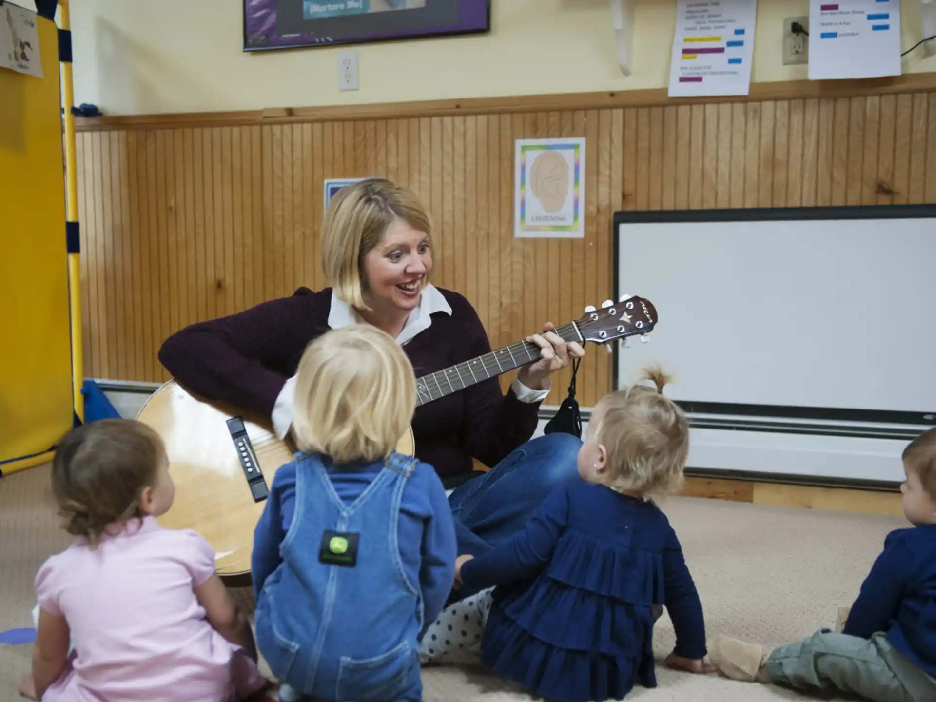a person playing a guitar in front of a group of children