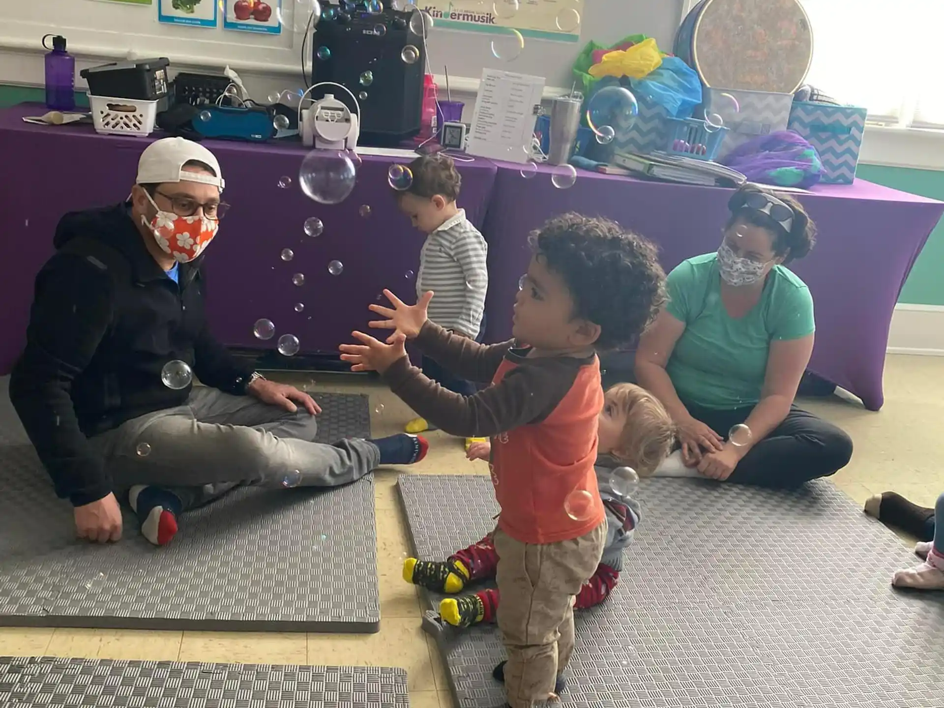 a group of people sitting on the floor with a child in a mask