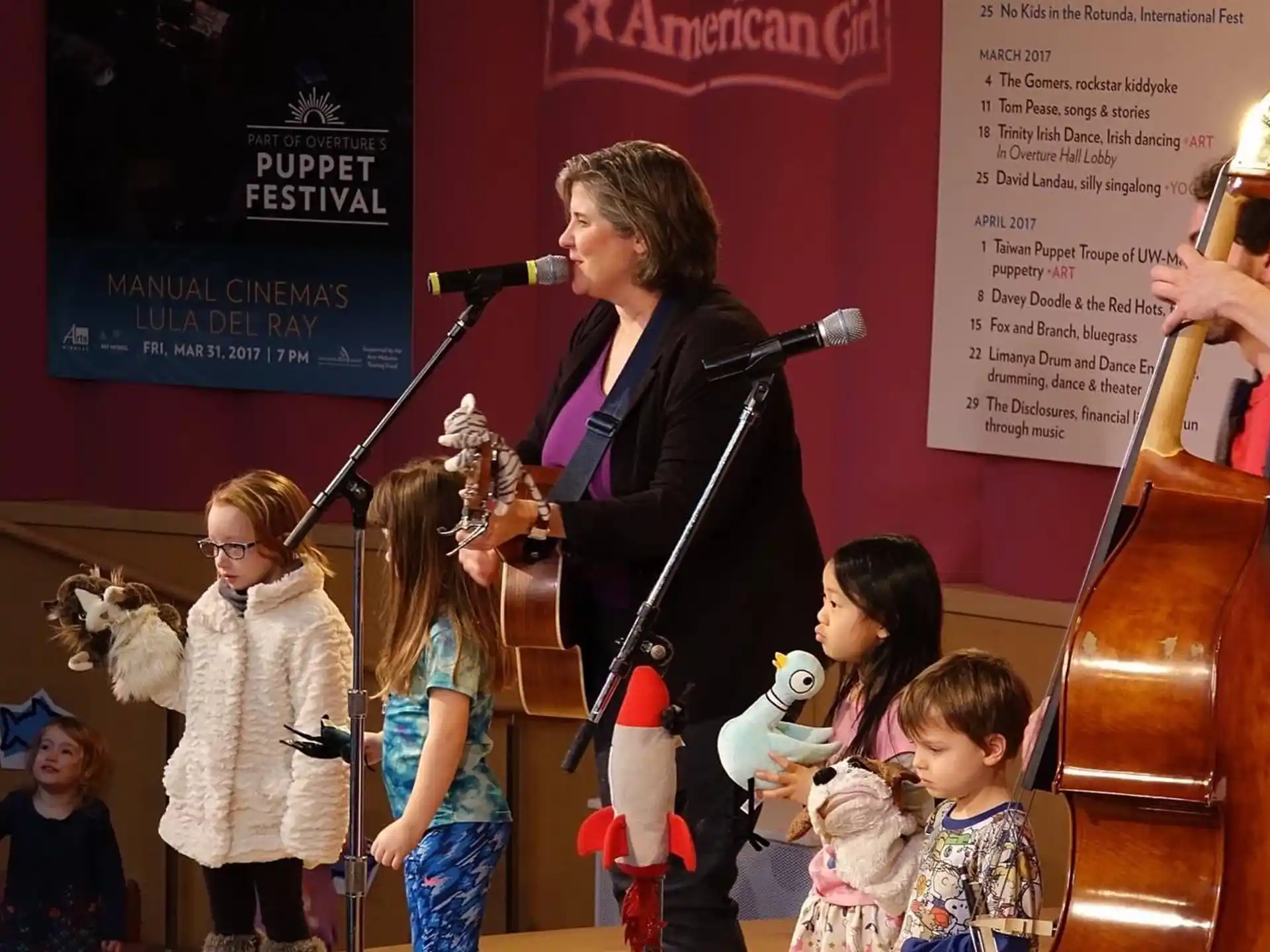 a person singing into a microphone with children around the