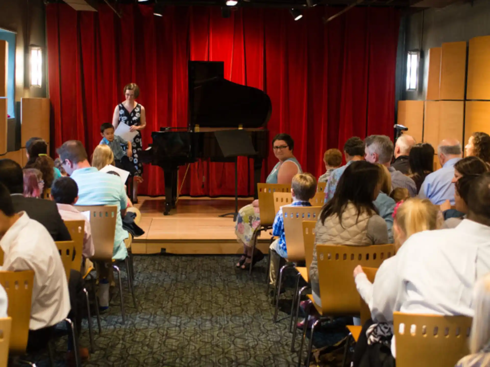 a group of people sitting in a room with a person standing in front of a podium