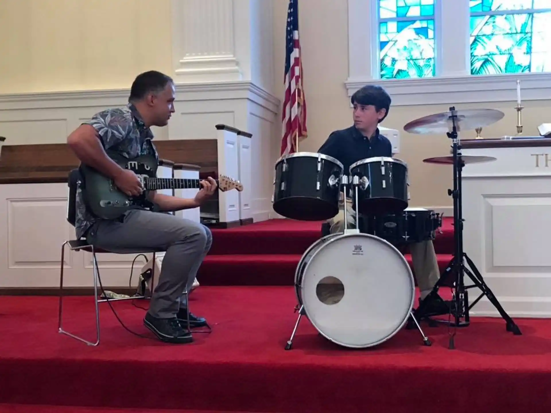 a man playing a guitar next to a man playing drums