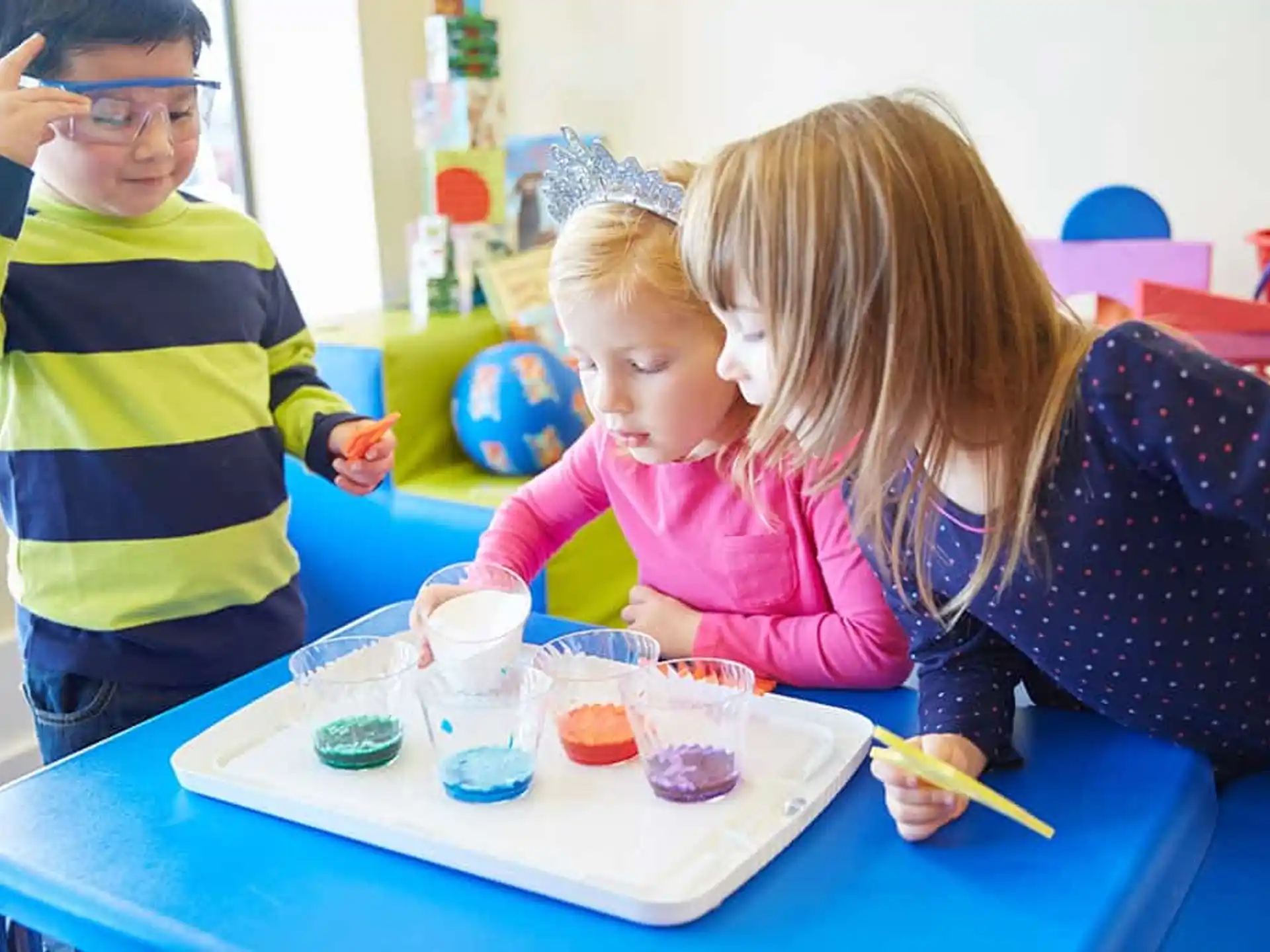 a couple of children sitting at a table with cups and a woman