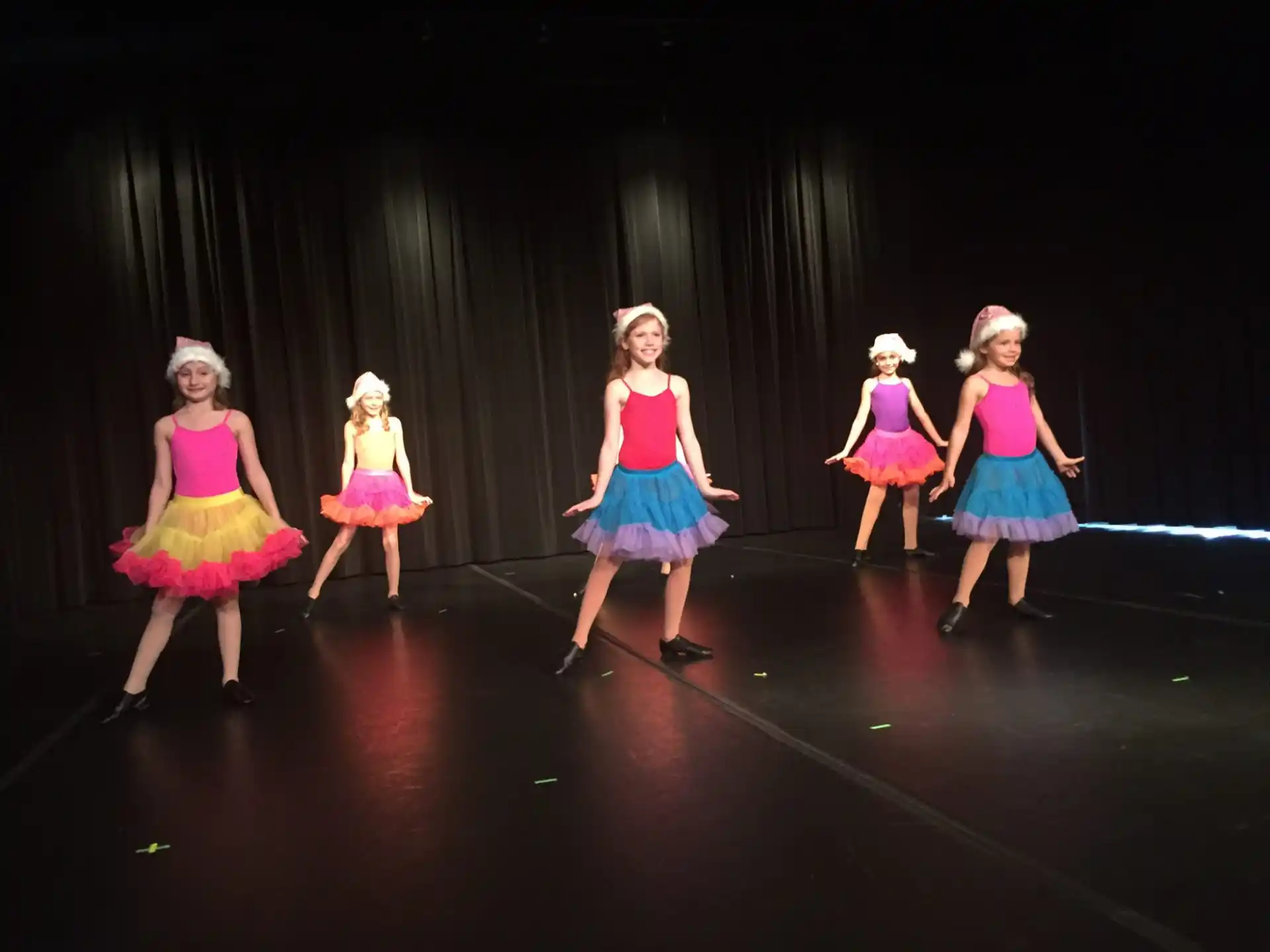 a group of girls in dresses on a stage