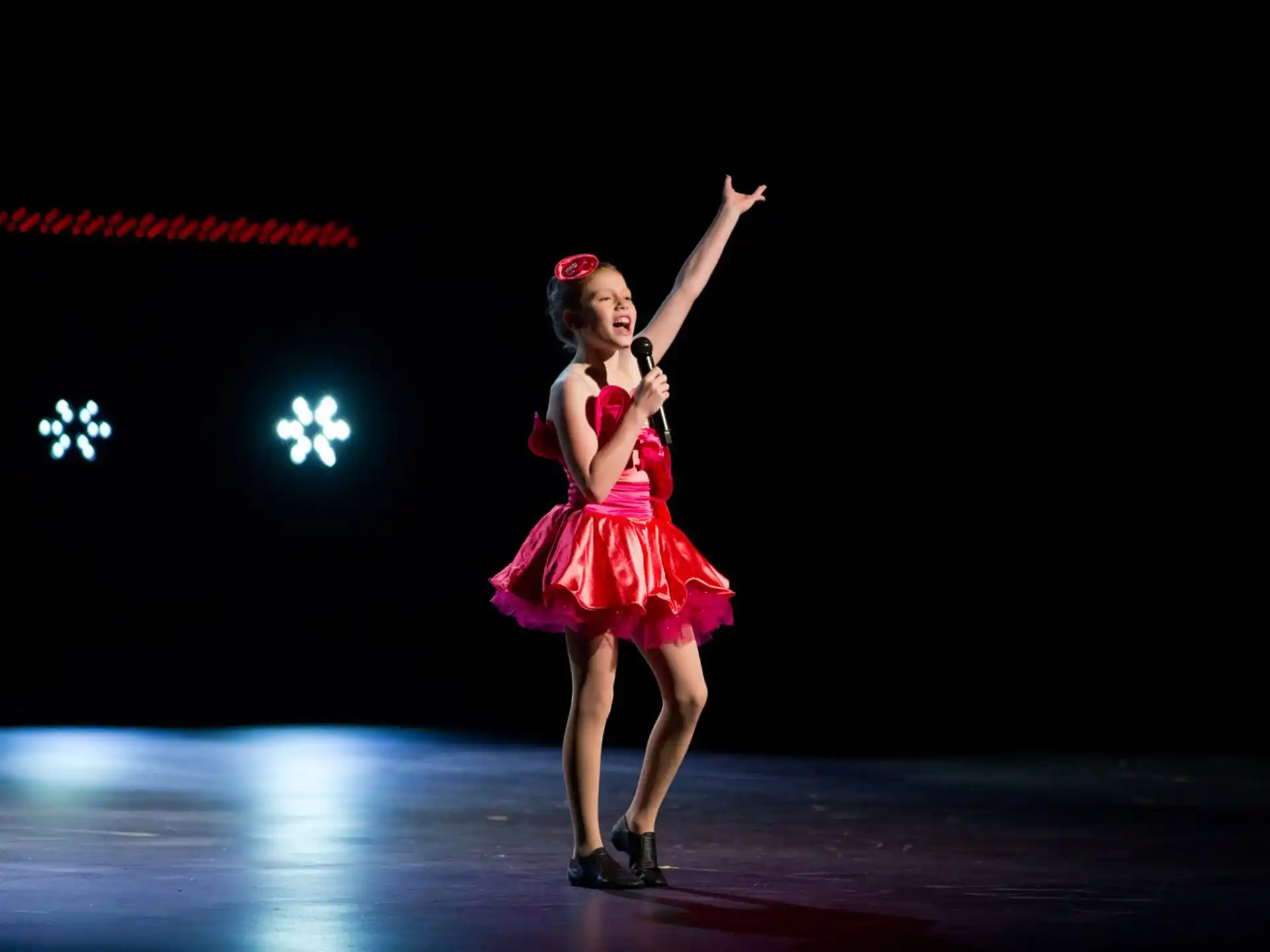 a person in a red dress on stage with the arms up