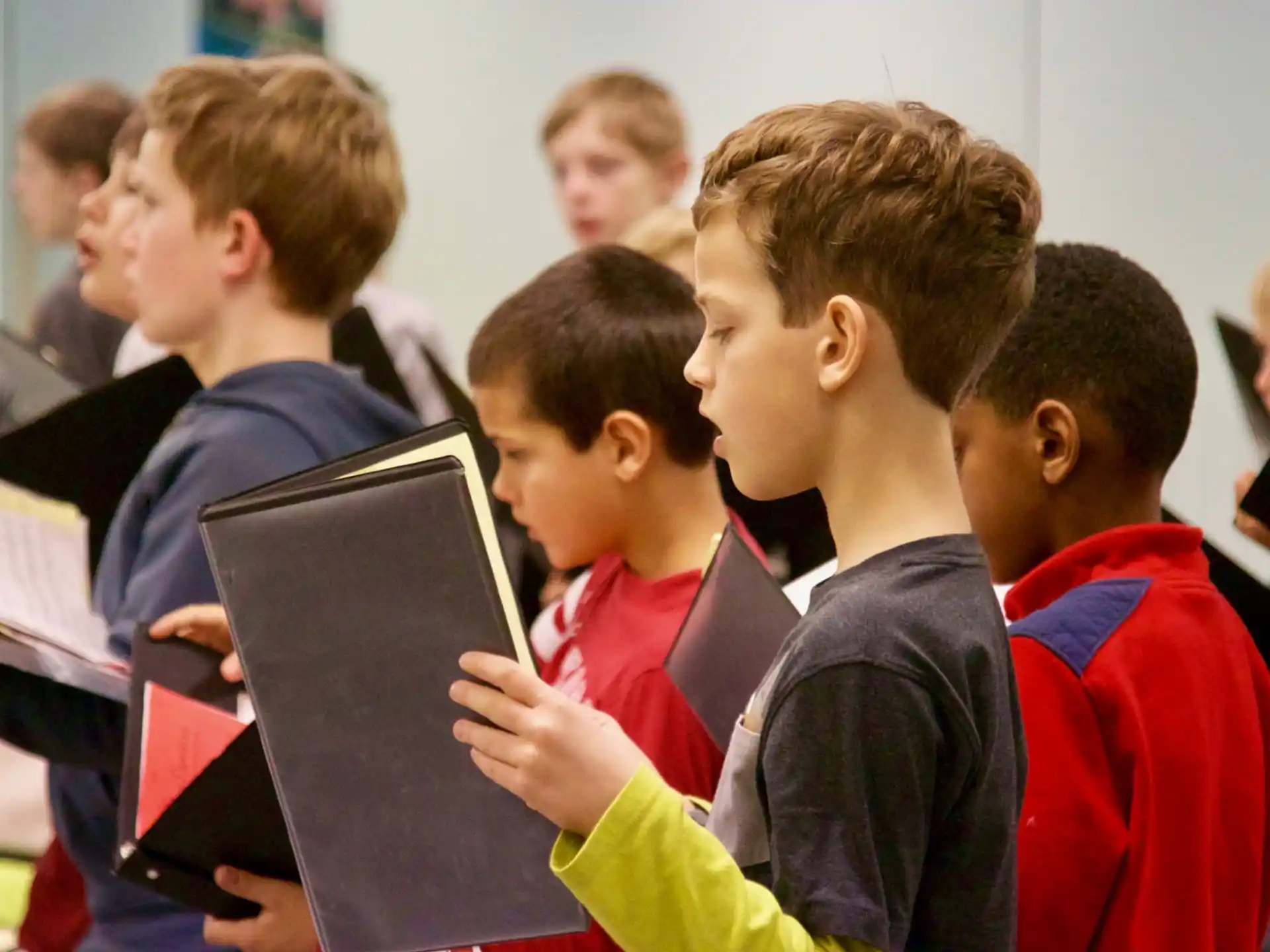 a group of children in red and blue uniforms reading books