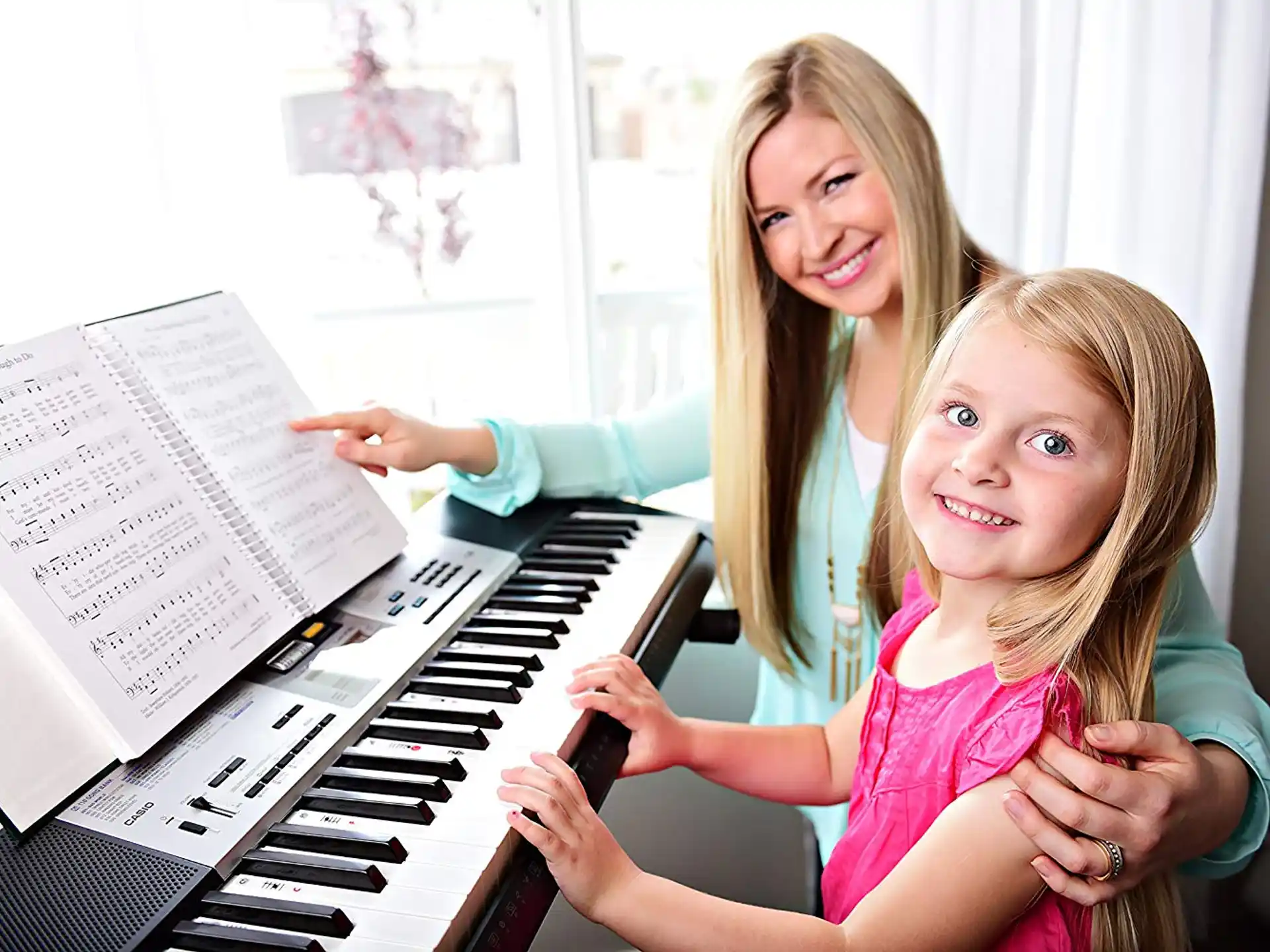 a woman and a girl playing piano