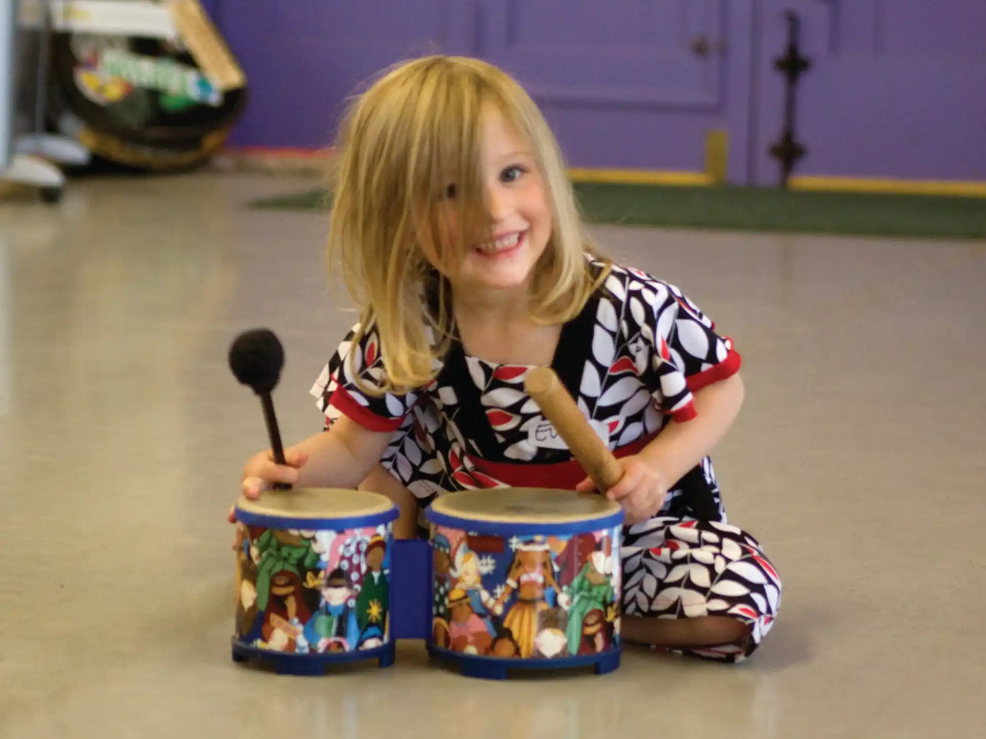 a girl sitting on the floor with a bucket of paint