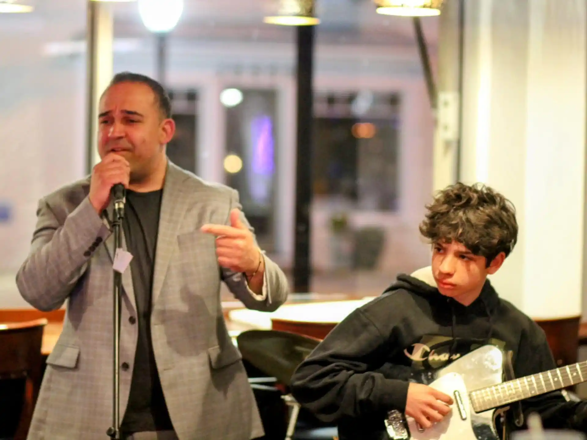 a man singing into a microphone next to a man playing guitar