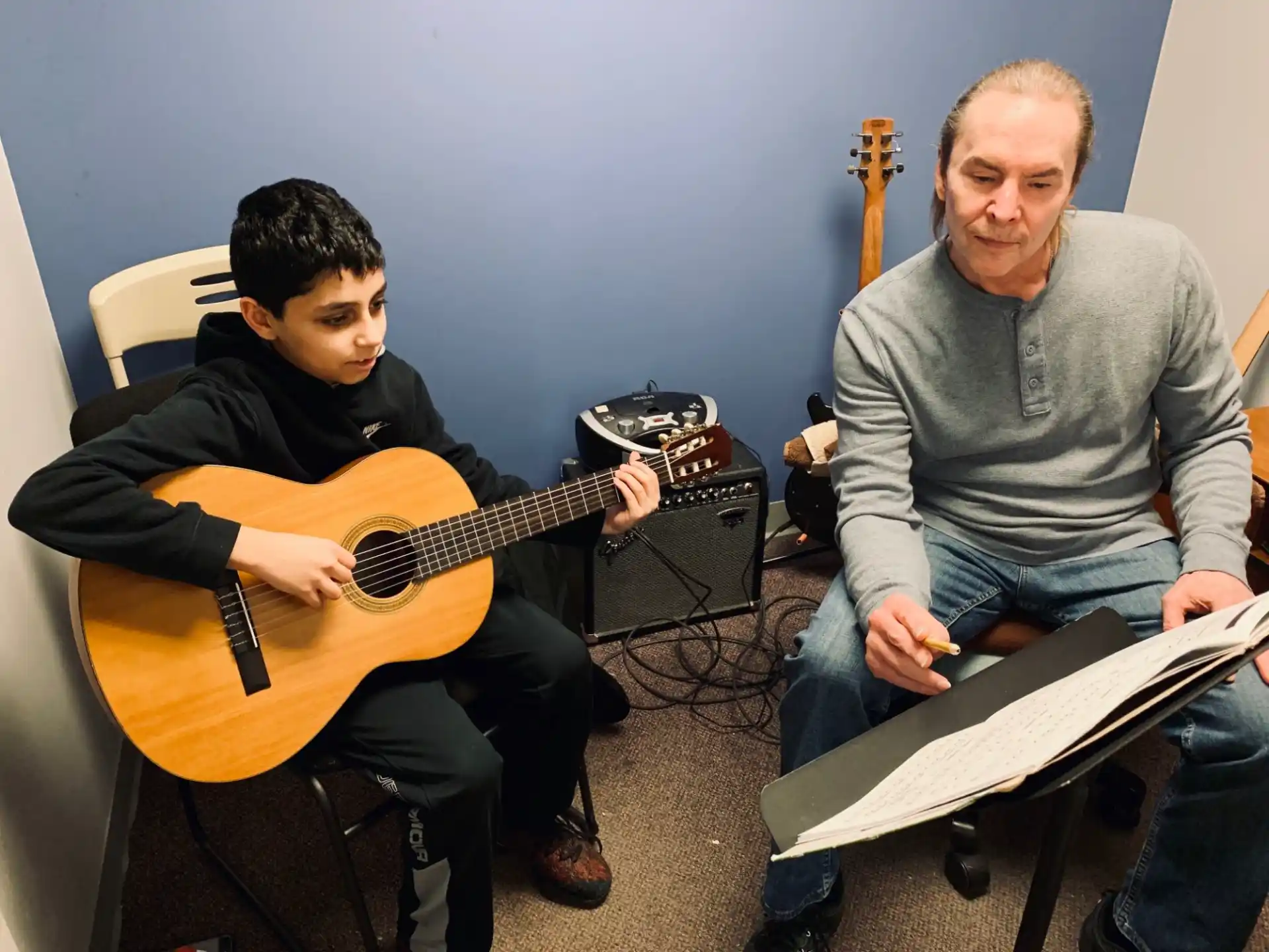 a man and a boy playing guitars