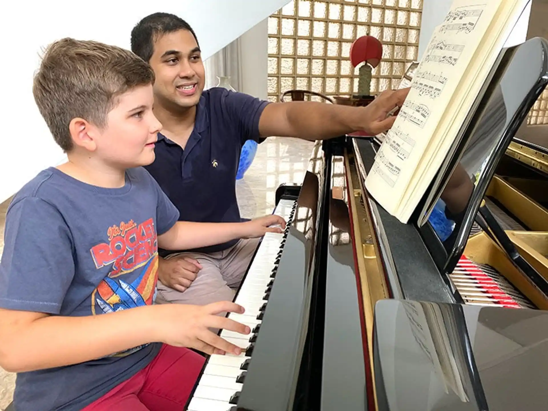 a person and a boy playing piano
