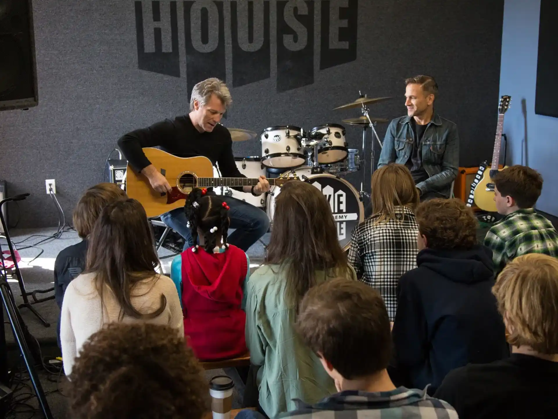 a group of people sitting in a room with a person standing in front of a microphone