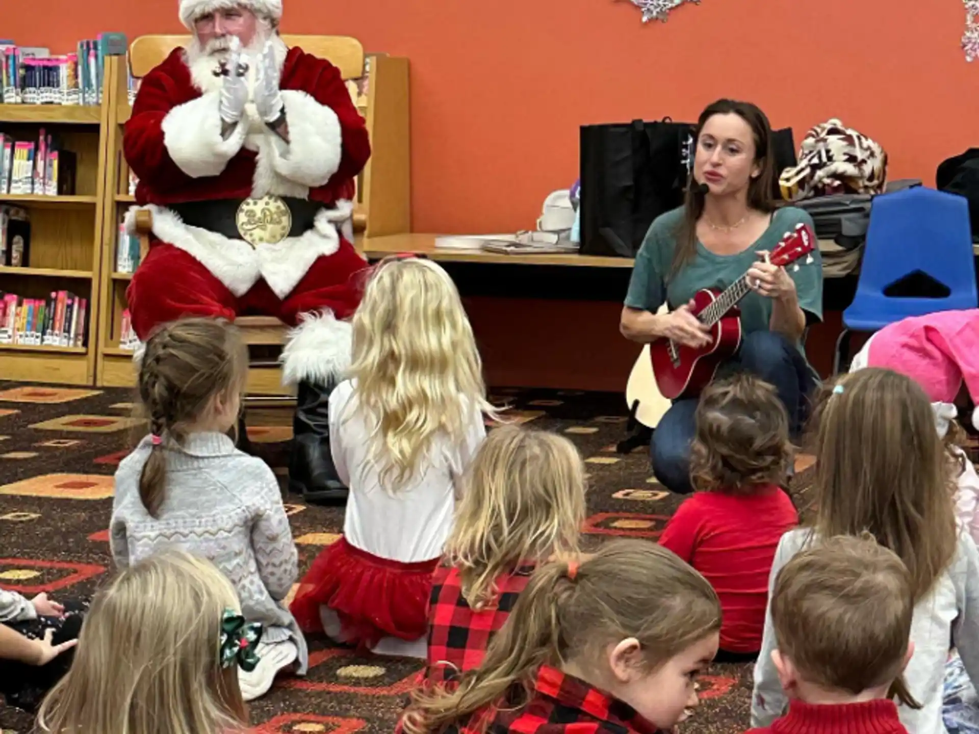 a man and woman playing guitar to a group of children