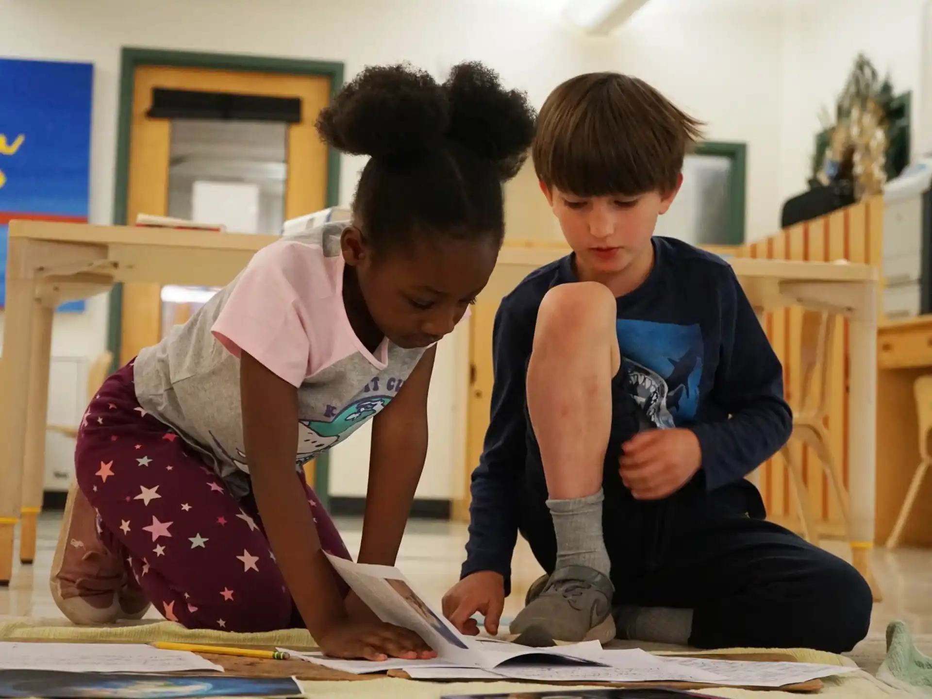 a couple of children sitting on the floor looking at a book