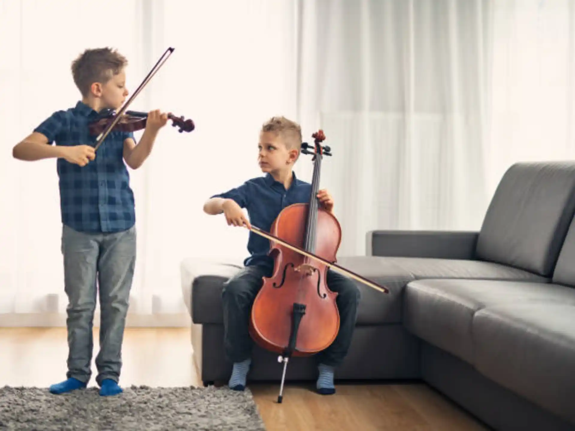 a boy playing a violin next to a girl playing a cello