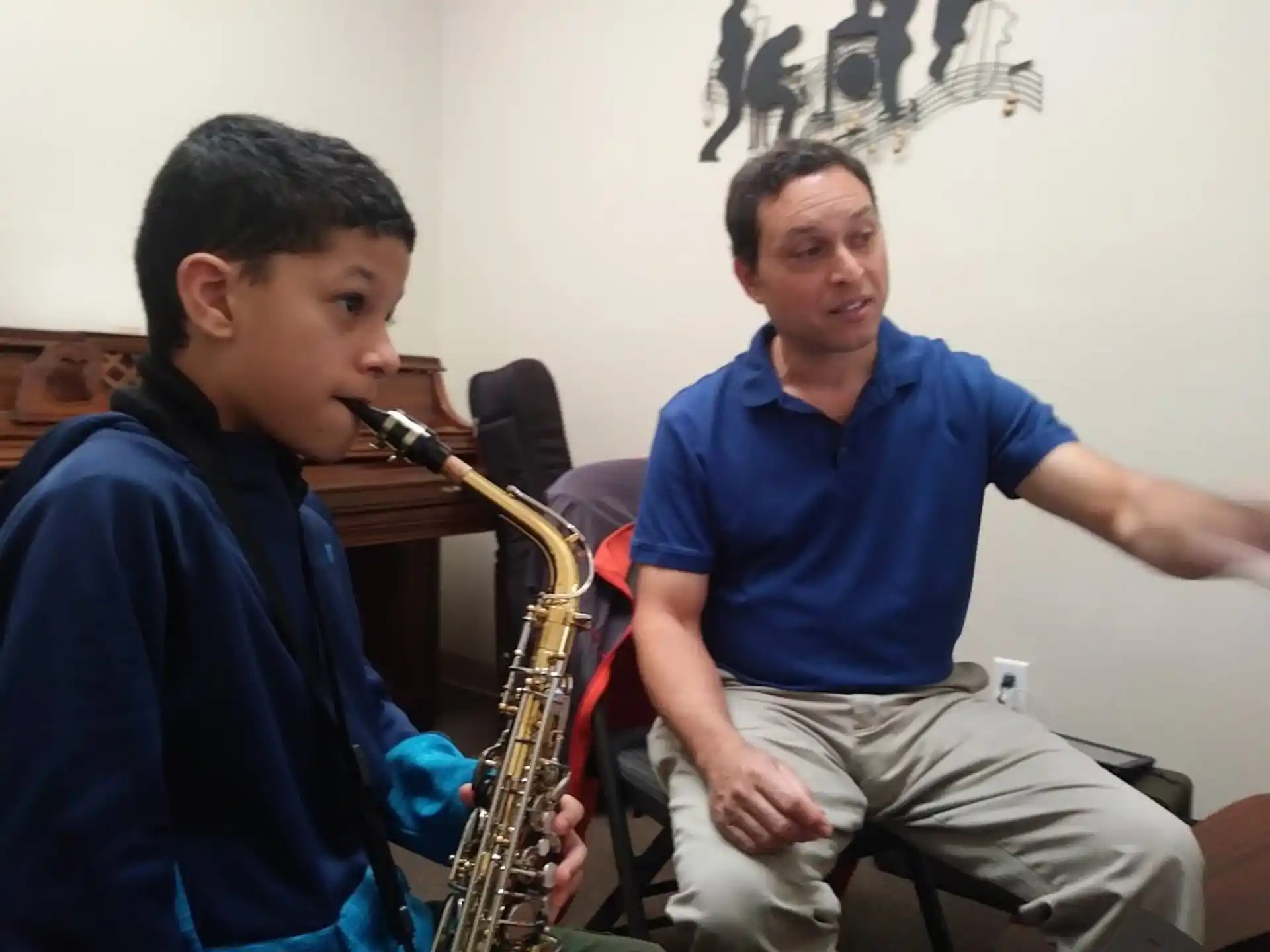 a man playing a saxophone next to a man sitting on a chair