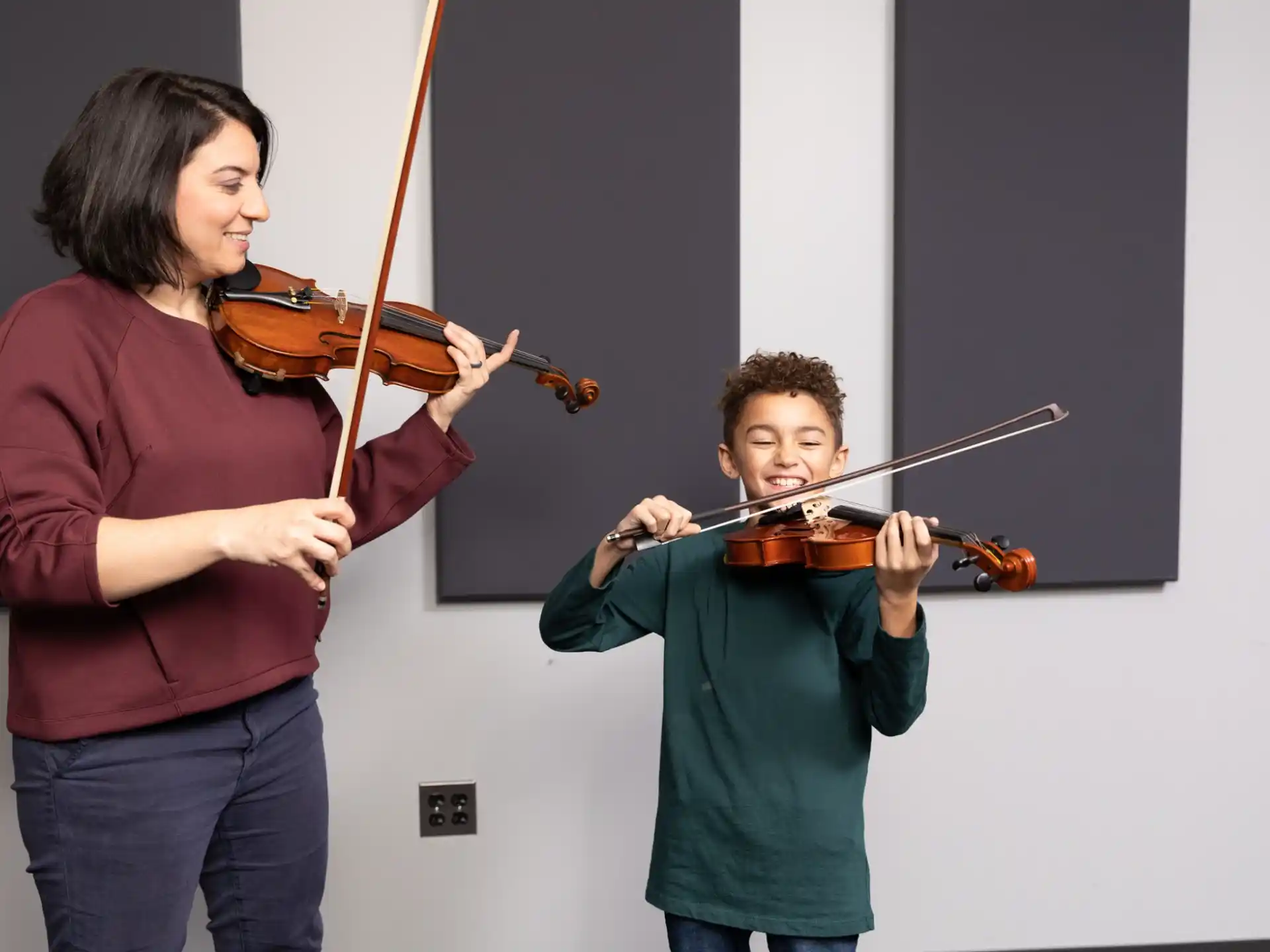 a person playing a violin next to a boy playing a violin