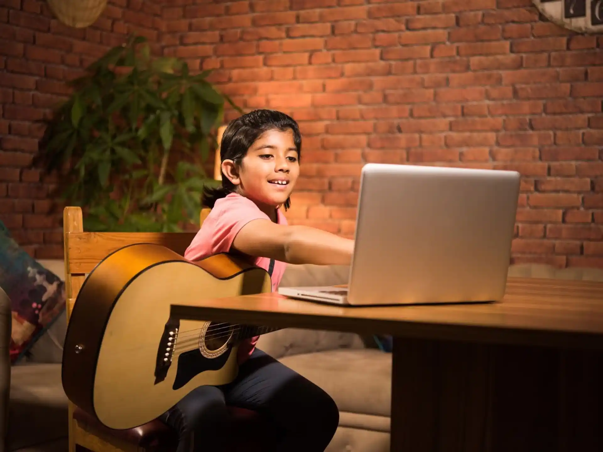 a person sitting at a desk with a laptop and a guitar