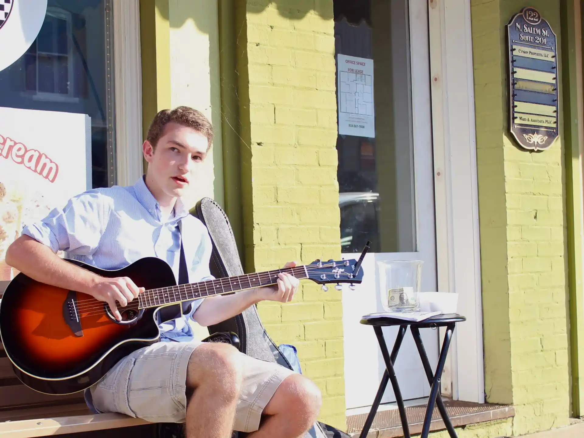 a person sitting on a stool playing a guitar
