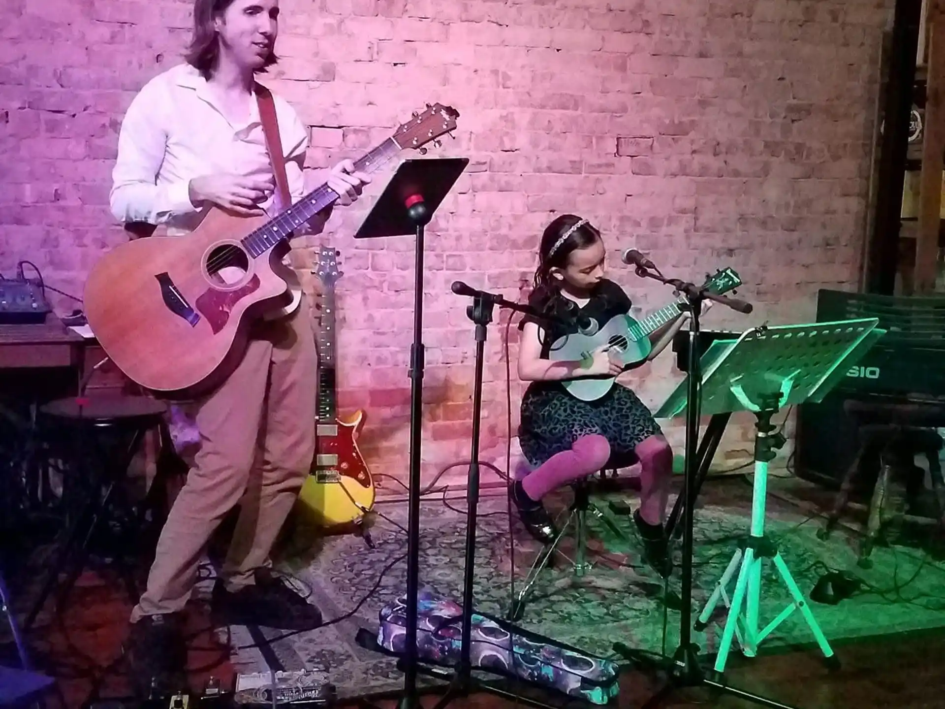 a person playing a guitar next to a girl playing a guitar