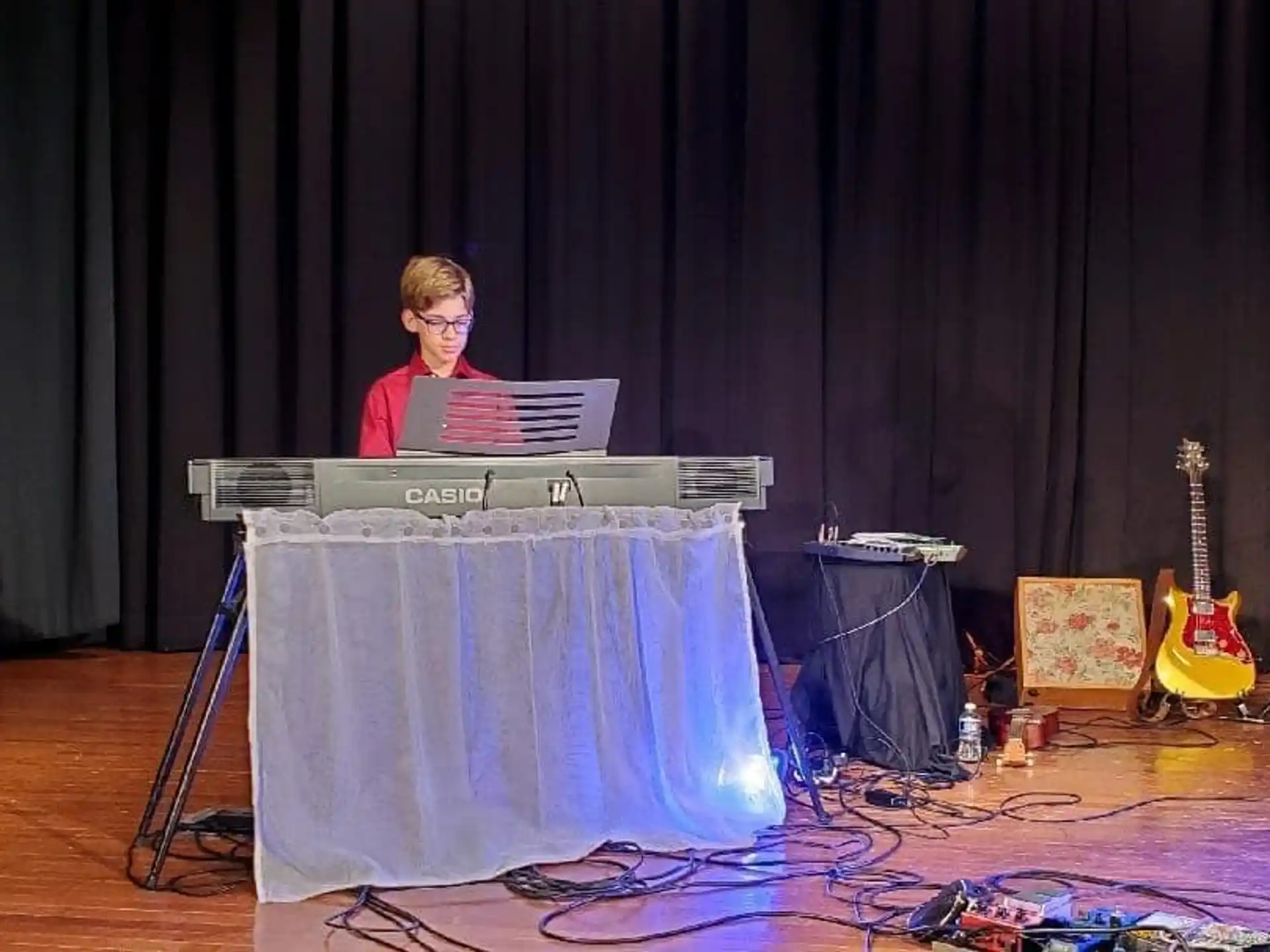 a person sitting at a podium with a microphone and a musical instrument