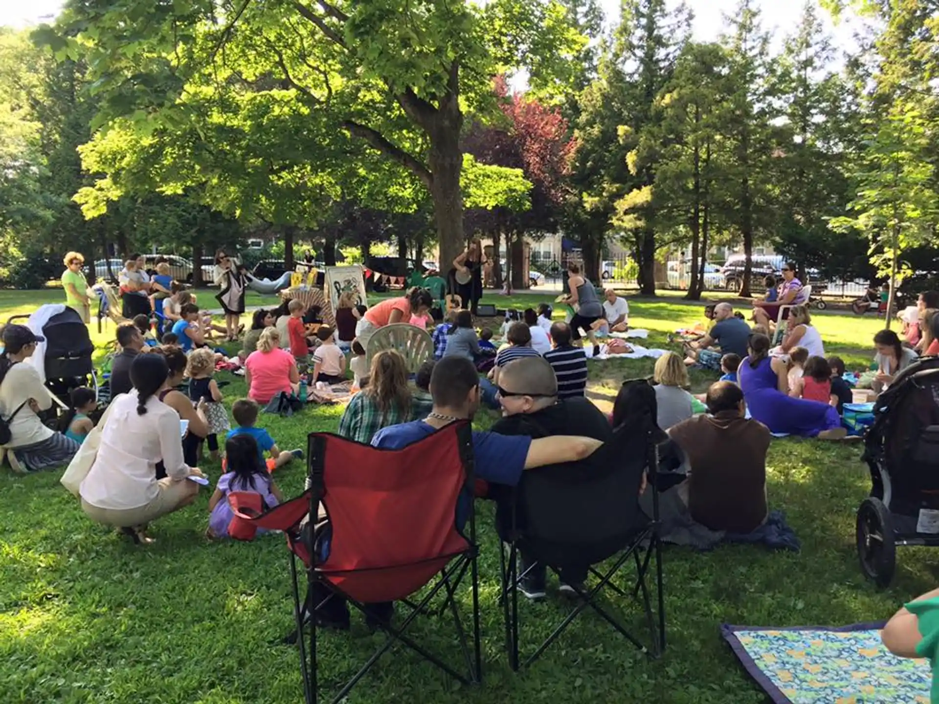a group of people sitting in chairs in a park