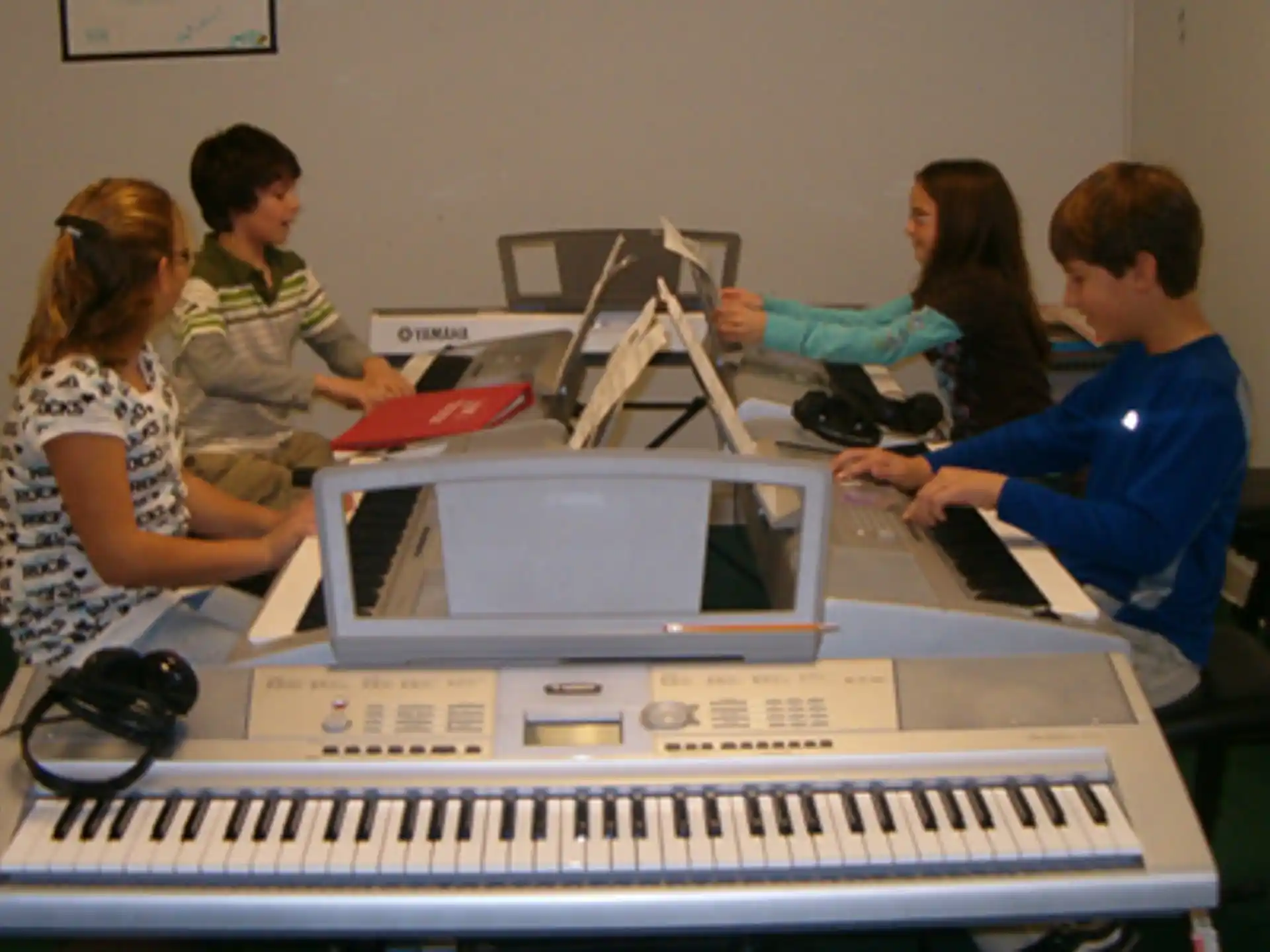 a group of people sitting at a table with a keyboard and a computer