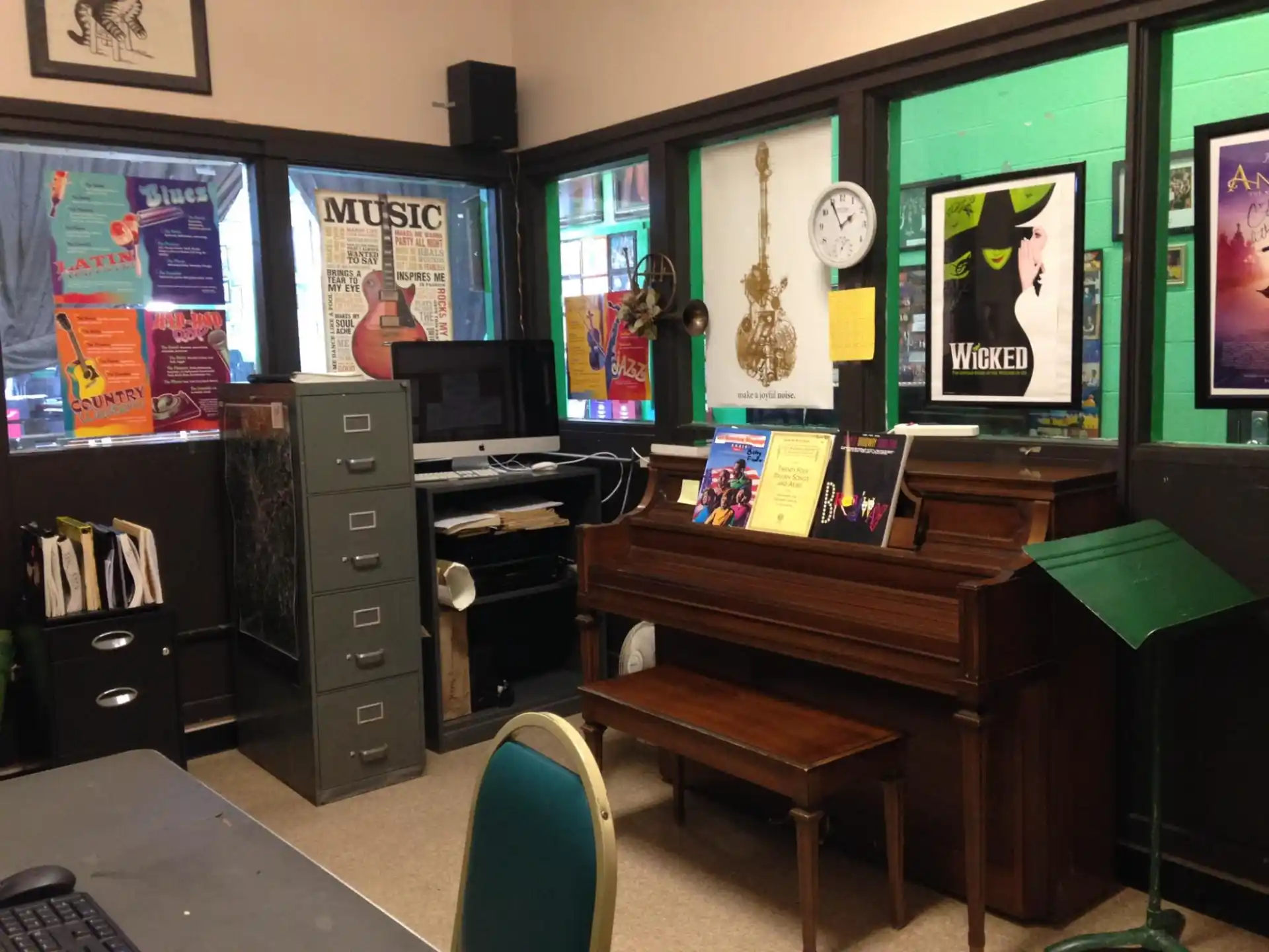 a room with a piano and posters on the wall