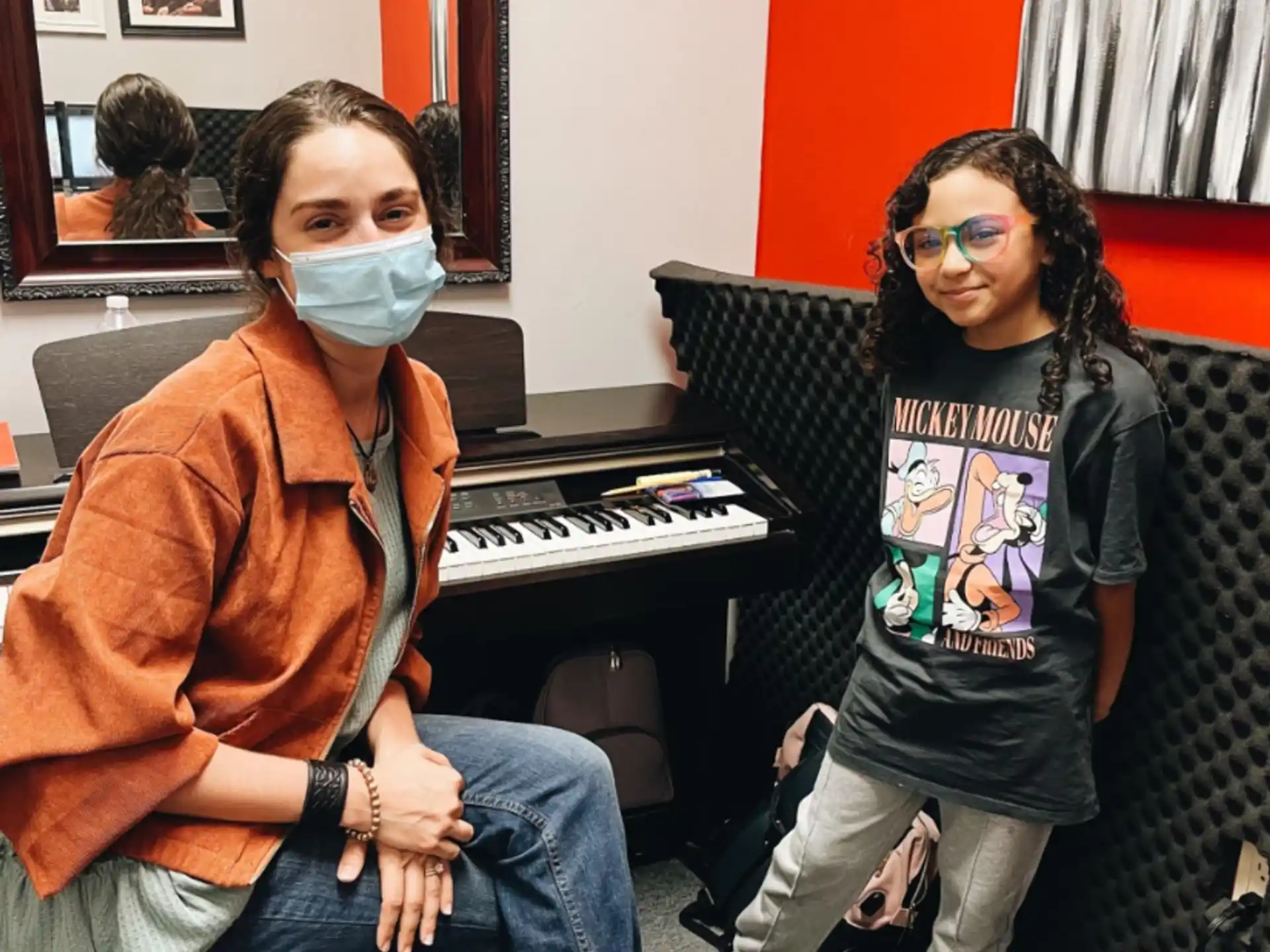 a couple of women sitting next to a piano