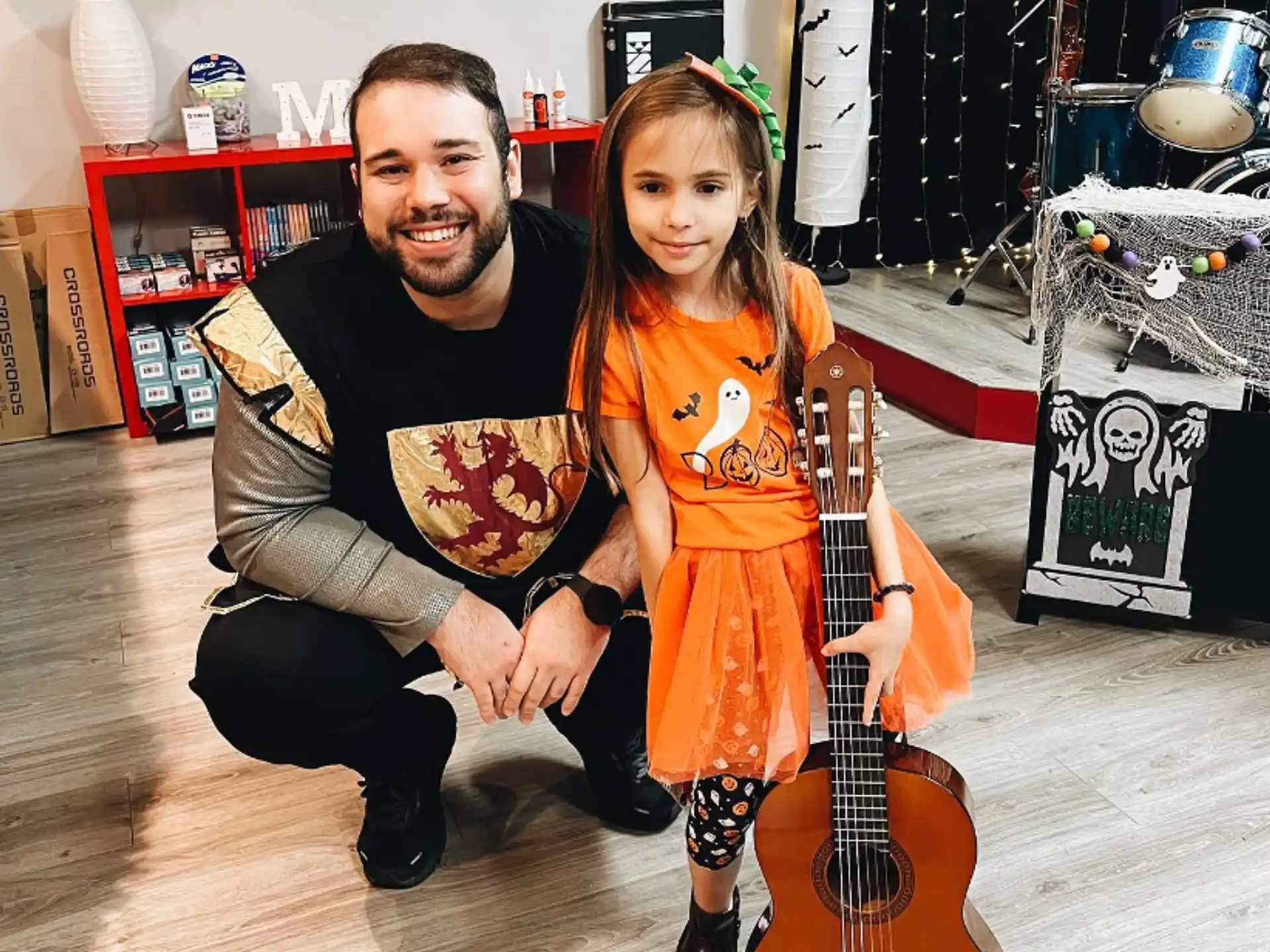 a person and a girl sitting on the floor holding a guitar
