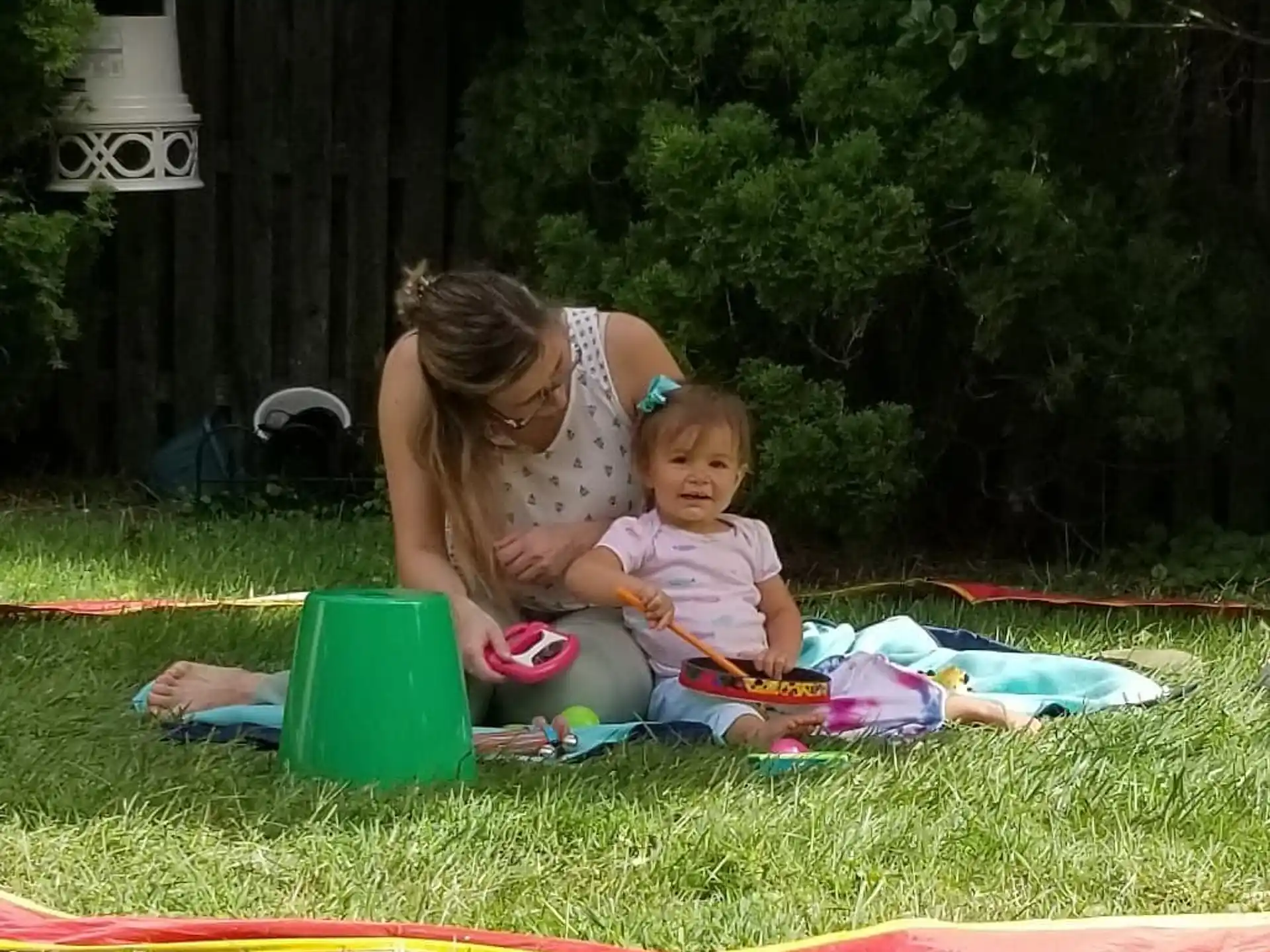 a person and a child sitting on a blanket in a grassy area