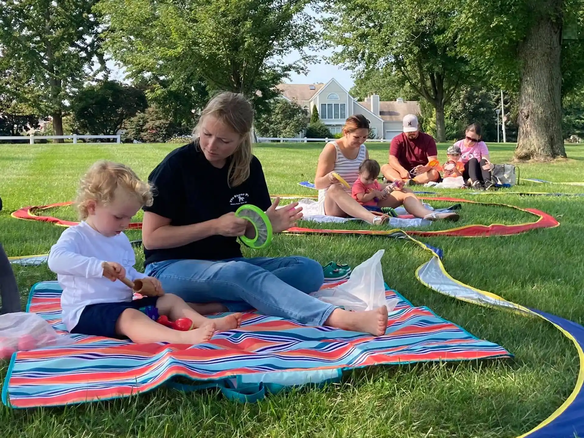 a person and a child sitting on a blanket in a grassy area