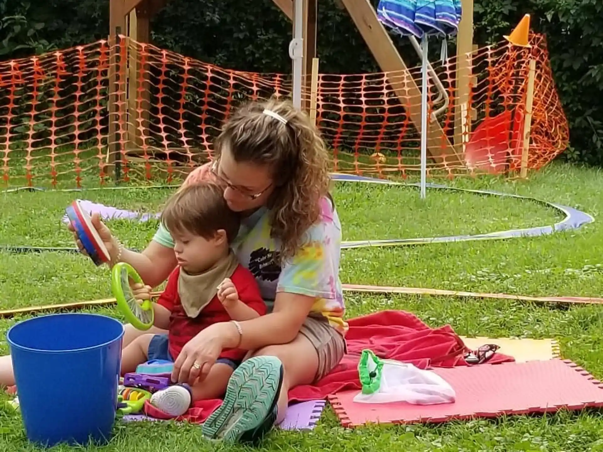 a person and a child sitting on a blanket in a grassy area