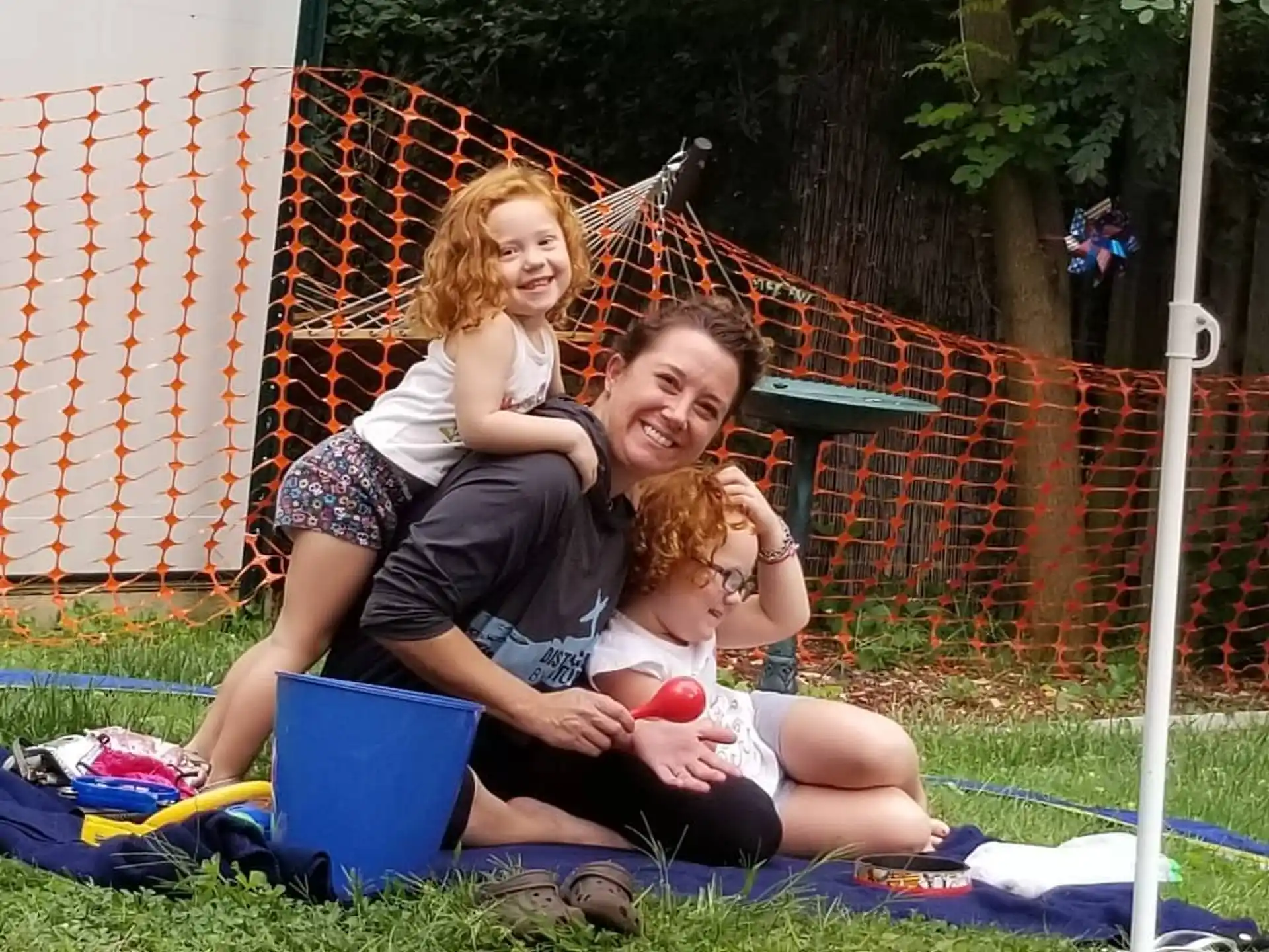 a woman and two children sitting on a blanket in a grassy area