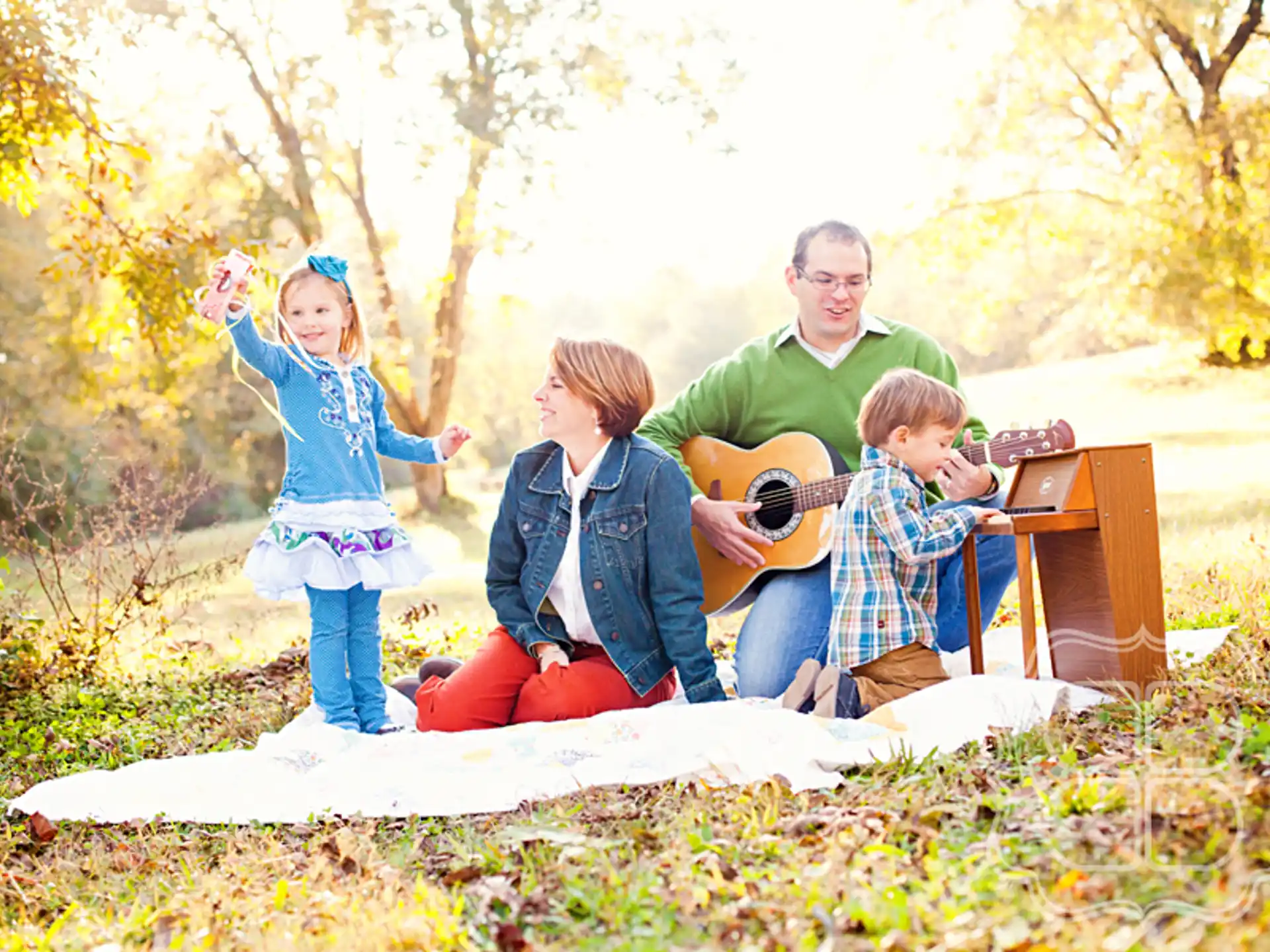 a group of people sitting on a blanket in a park